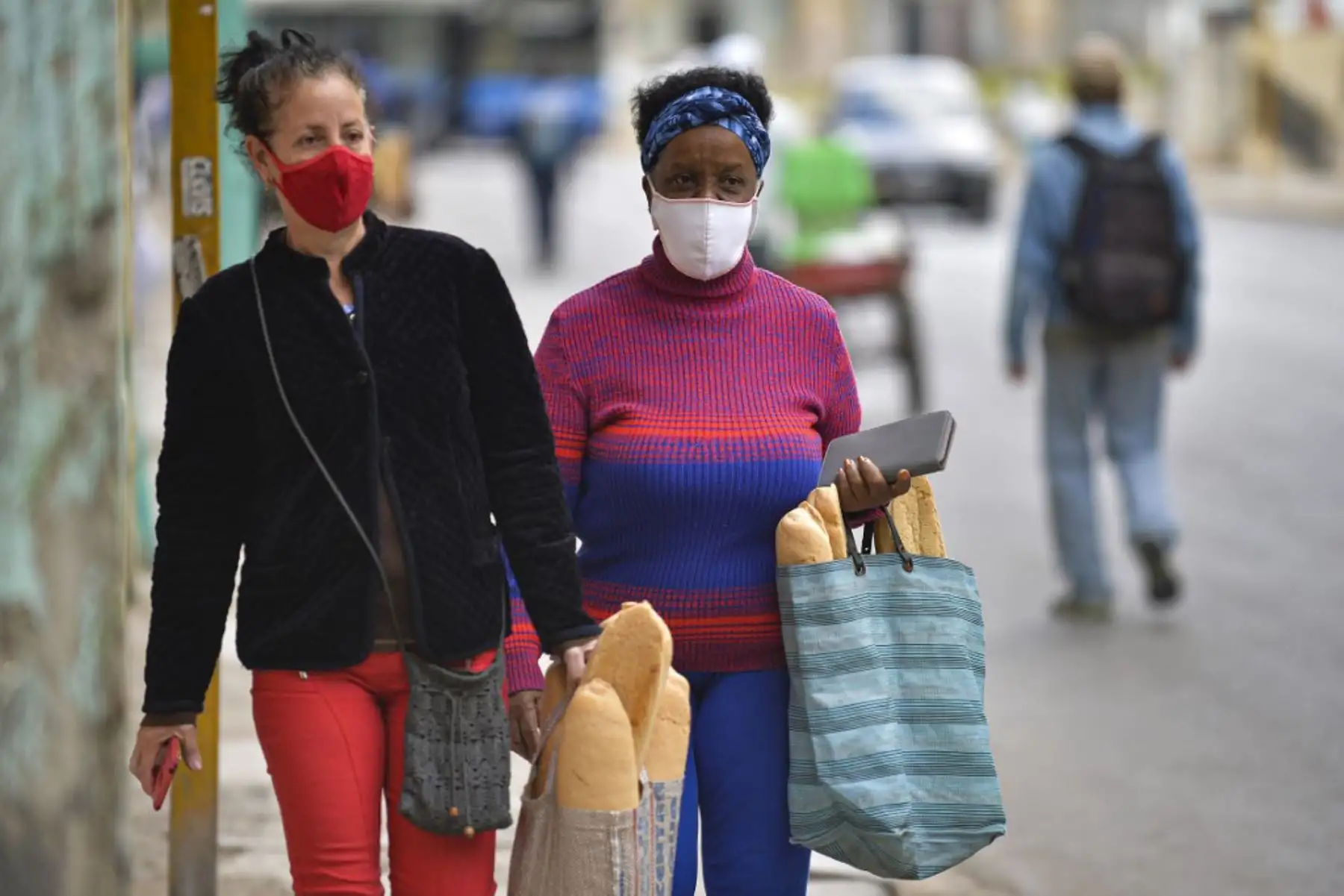 Las mujeres usan máscaras faciales mientras caminan después de comprar pan en La Habana, mientras aumentan los casos de covid-19 en la nación isleña. Foto: AFP
