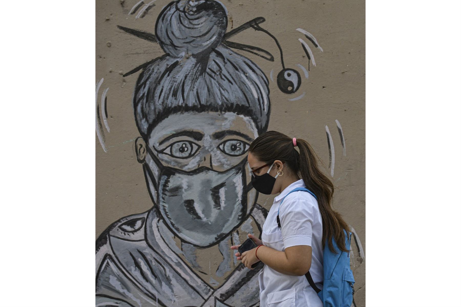 Una mujer con máscara facial camina en La Habana, mientras aumentan los casos de covid-19 en la nación insular. Foto: AFP