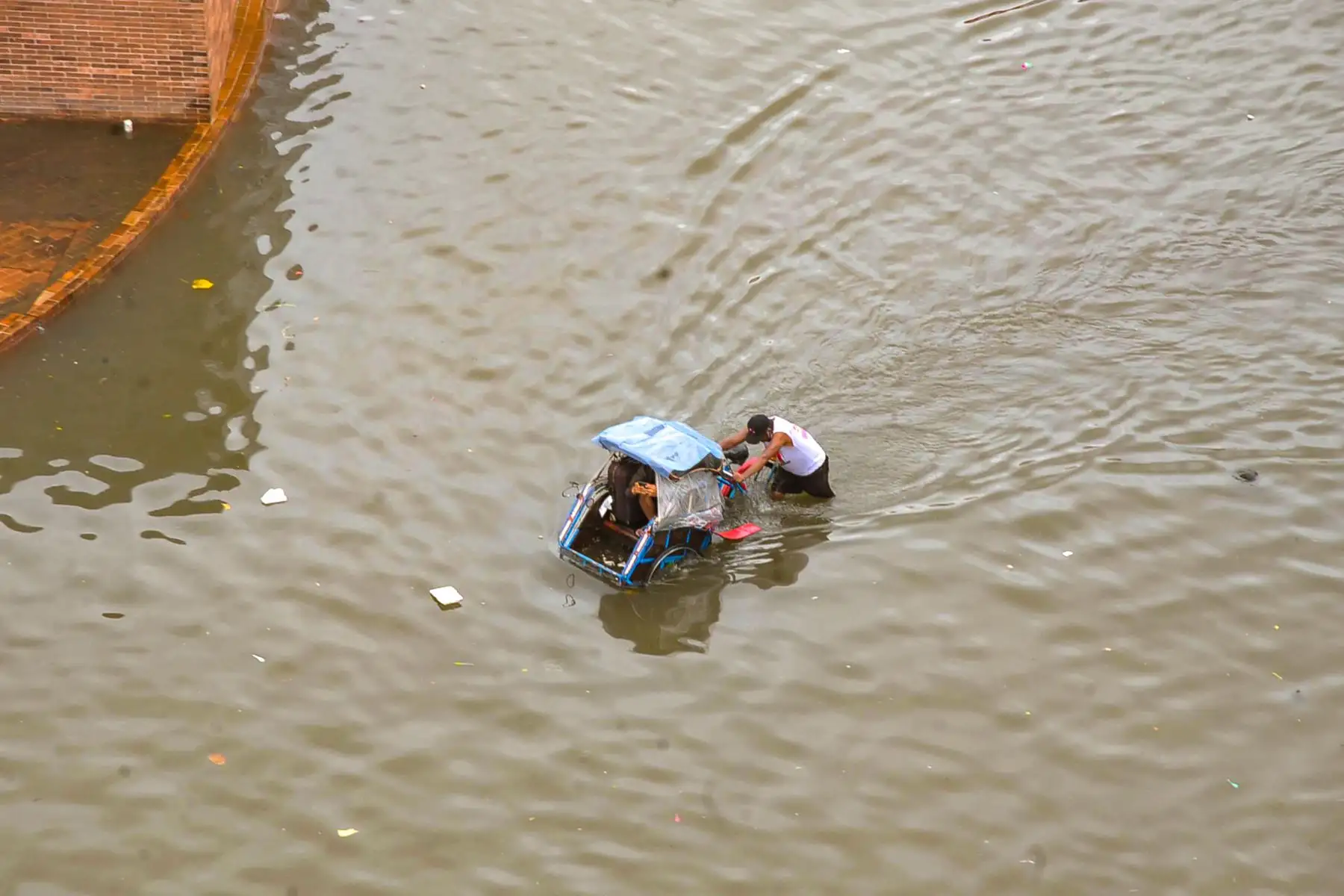 Un hombre empuja su bicitaxi con pasajeros a través de un área inundada causada por lluvias torrenciales en la ciudad de Semarang, Java central.
Foto: AFP