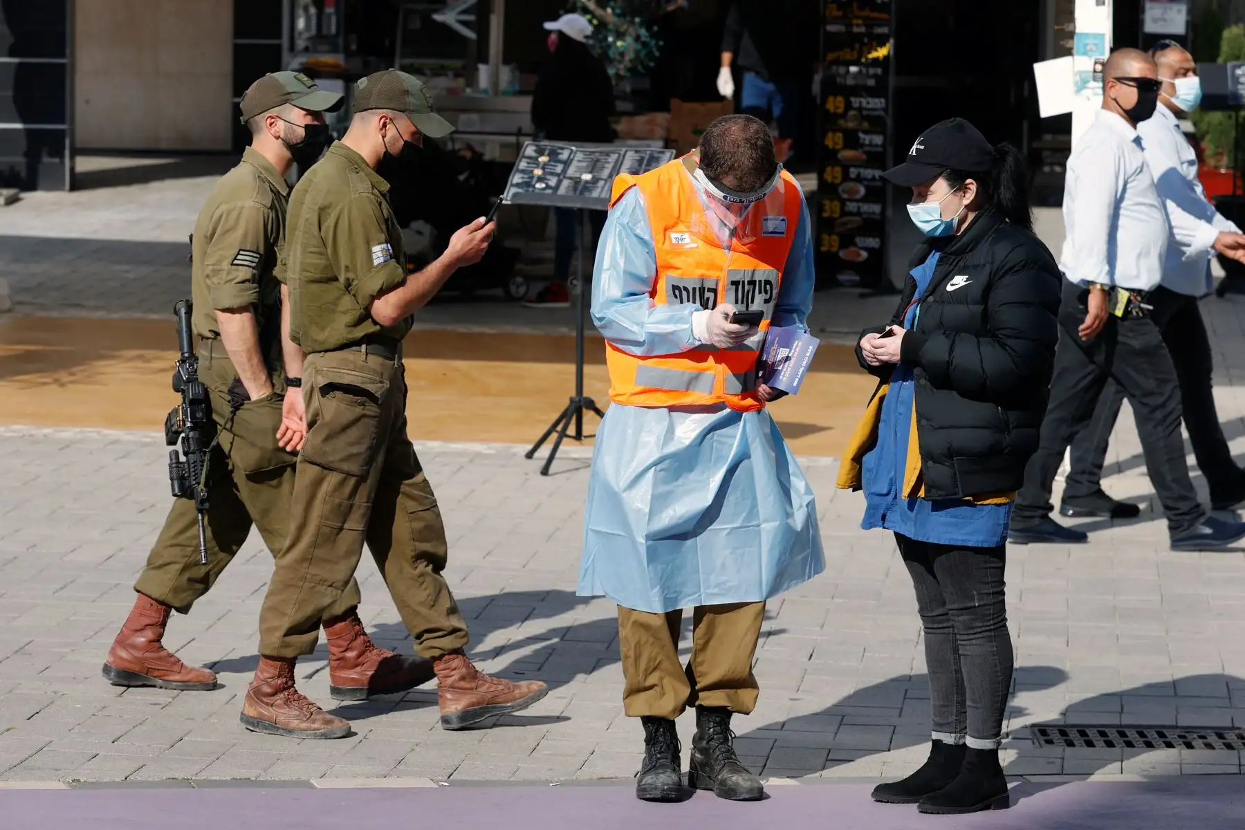 Un soldado del Home Front Command de Israel guía a un residente para encontrar una carpa de prueba de covid-19 en la ciudad turística central de Netanya, en Israel.
Foto: AFP