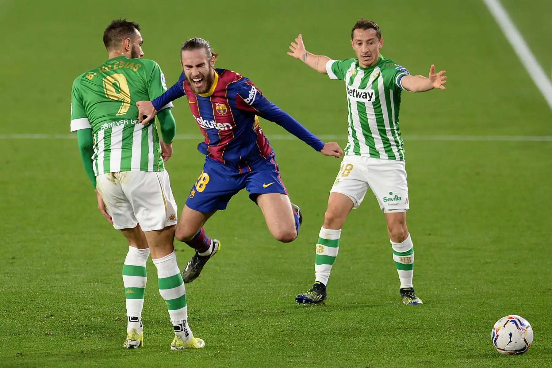 El defensor español del Barcelona Oscar Mingueza desafía al delantero español del Real Betis, Borja Iglesias, y al mediocampista mexicano del Real Betis, Andrés Guardado, durante el partido de fútbol de la liga española entre el Real Betis y el FC Barcelona. Foto: AFP