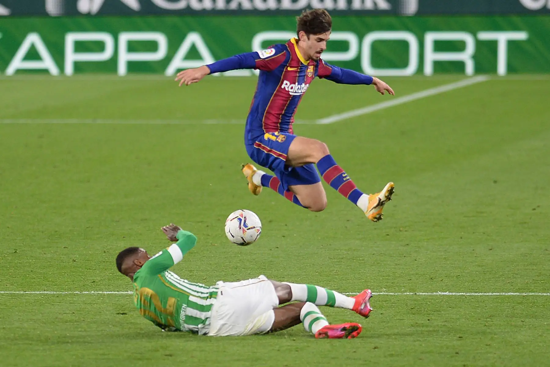 El delantero portugués del Barcelona Francisco Trincao, salta sobre el defensor brasileño del Real Betis, Emerson Royal, durante el partido de fútbol de la liga española entre el Real Betis y el FC Barcelona en el estadio Benito Villamarín de Sevilla. Foto: AFP