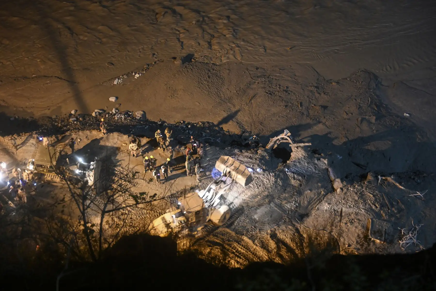 Las excavadoras y los equipos de rescate trabajan de noche en la entrada de un túnel bloqueado con barro y escombros durante las operaciones de rescate en Tapovan del distrito de Chamoli, luego de una inundación repentina que se cree que fue causada cuando un glaciar estalló.
Foto: AFP