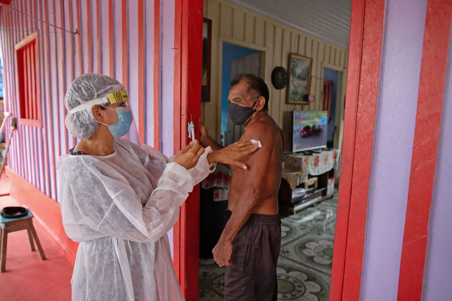 Joao Aquino Filho, de 71 años, es inmunizado por un trabajador de la salud con una dosis de la vacuna COVID-19 Oxford-AstraZeneca en la comunidad de Nossa Senhora Livramento en las orillas del Río Negro cerca de Manaus, Amazonas, en Brasil. Foto: AFP