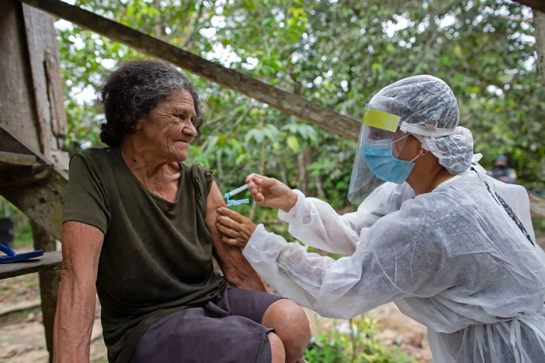 Maria Ferreira, de 74 años, es inmunizada por una trabajadora de la salud con una dosis de la vacuna COVID-19 Oxford-AstraZeneca en la comunidad Nossa Senhora Livramento a orillas del Río Negro cerca de Manaus, Amazonas, en Brasil. Foto: AFP