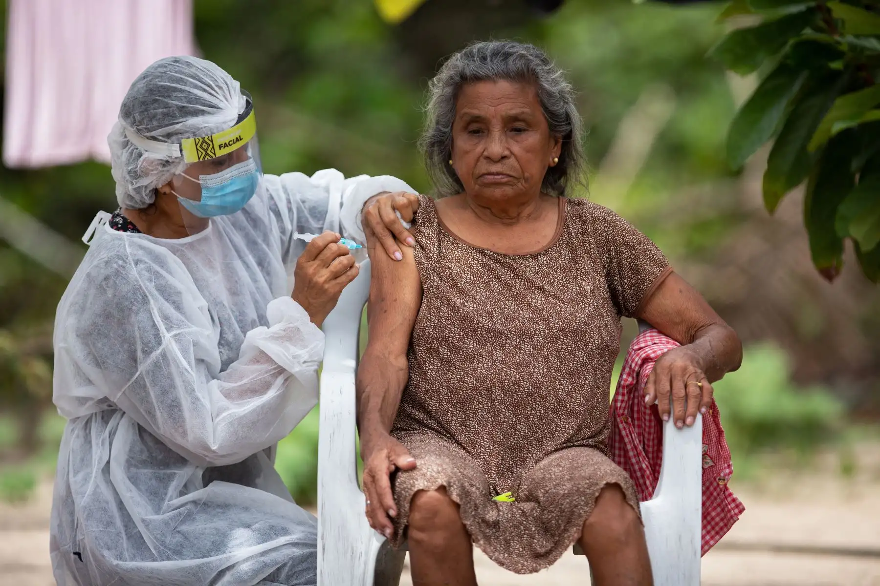 Rosina Ruiz Carvalho, de 76 años, es inmunizada por una trabajadora de la salud con una dosis de la vacuna COVID-19 Oxford-AstraZeneca en la comunidad de Nossa Senhora Livramento a orillas del Río Negro cerca de Manaus, Amazonas, en Brasil. Foto: AFP