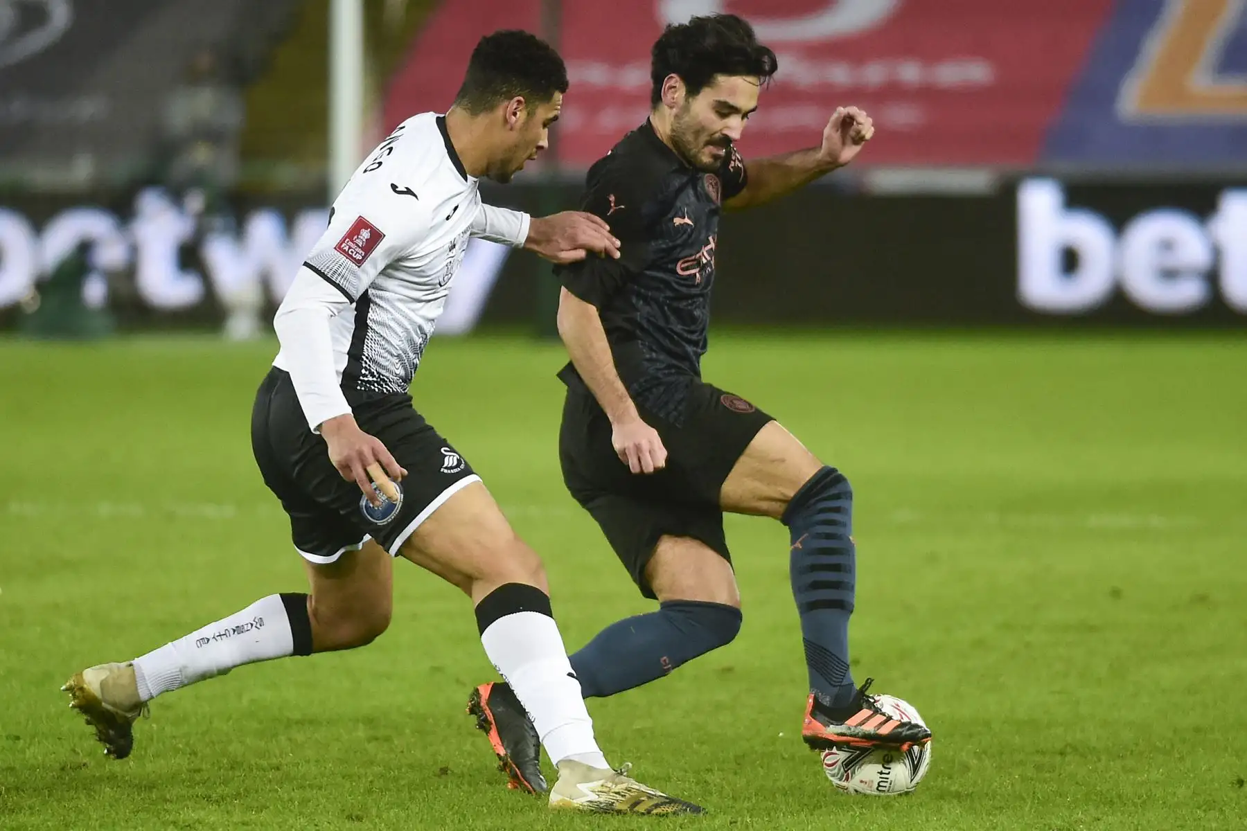 El defensa galés del Swansea City, Ben Cabango compite con el mediocampista alemán del Manchester City, Ilkay Gundogan, durante el partido de fútbol de la quinta ronda de la Copa FA inglesa. Foto: AFP