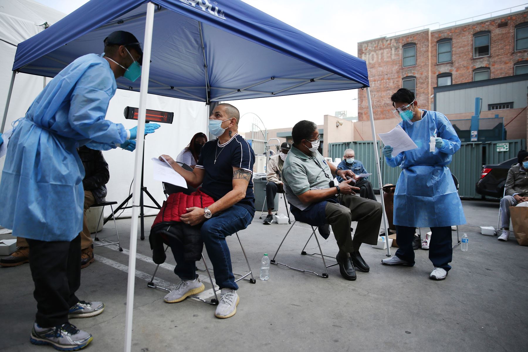 Héctor Ortiz habla con un trabajador de la salud después de recibir una dosis de la vacuna Moderna COVID-19 fuera de la Misión de Los Ángeles ubicada en la comunidad de Skid Row, en Estados Unidos. Foto: AFP