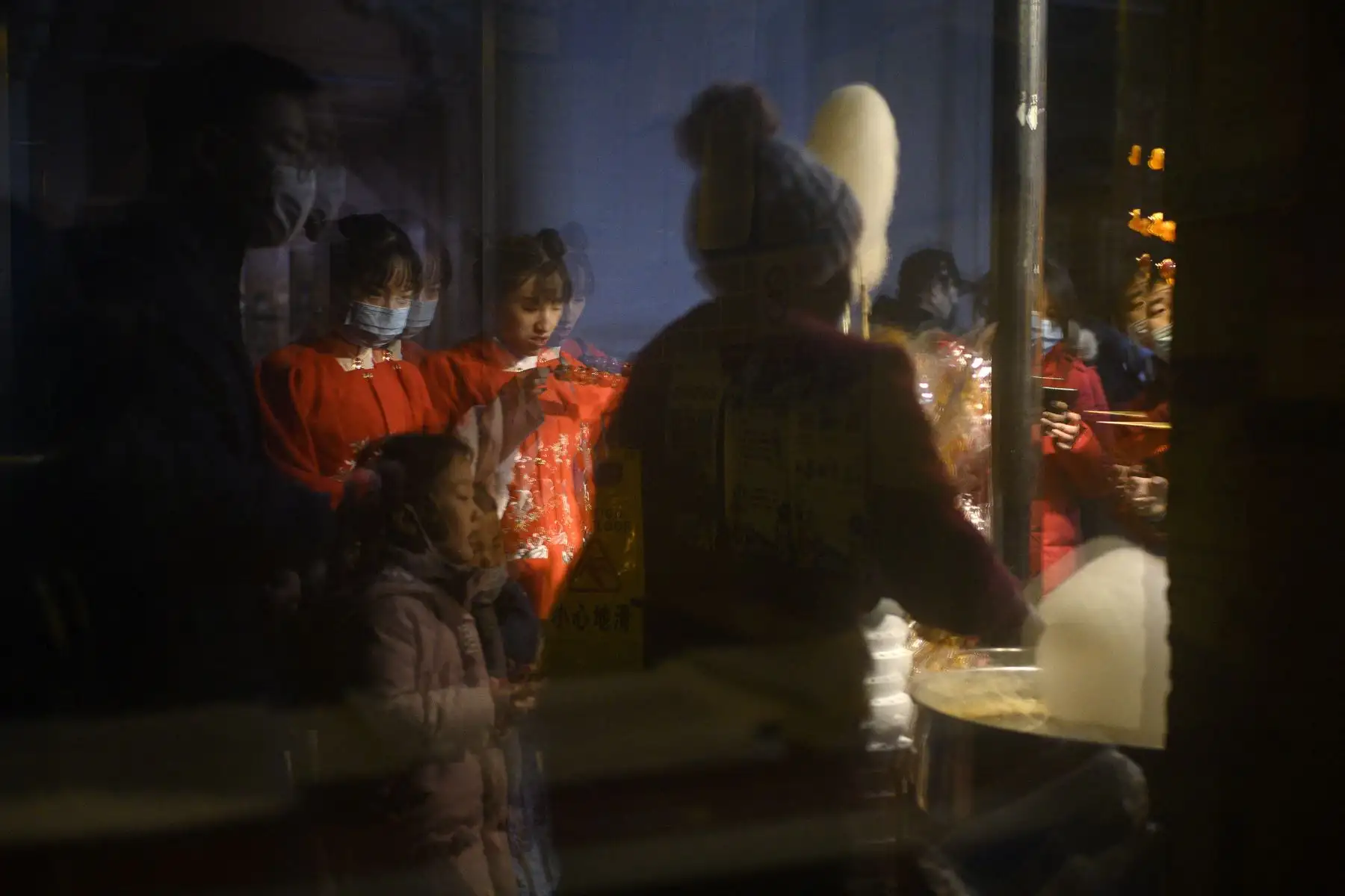 Las personas se reflejan en un espejo en la calle Qianmen en Beijing el 11 de febrero de 2021, antes del Año Nuevo Lunar, que marca el comienzo del Año del Buey. Foto: AFP
