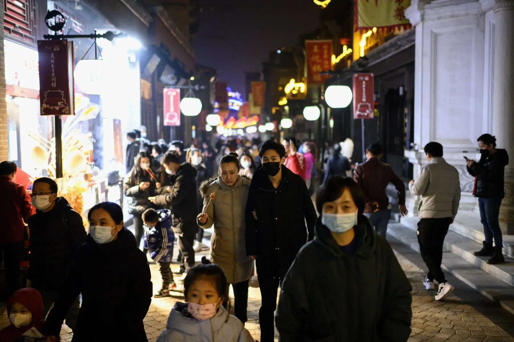Personas con máscaras caminan por la calle Qianmen en Beijing el 11 de febrero de 2021, antes del Año Nuevo Lunar. Foto: AFP