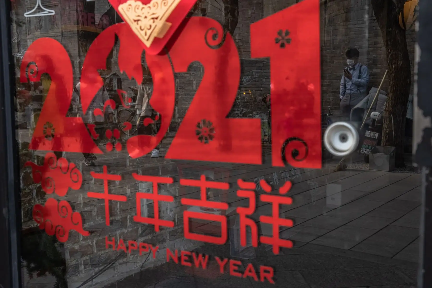 Un hombre se refleja en la puerta de un café mientras se encuentra en el callejón Nanluoguxiang en vísperas del Año Nuevo Lunar, en el barrio Hutong de Beijing, China. Foto: EFE