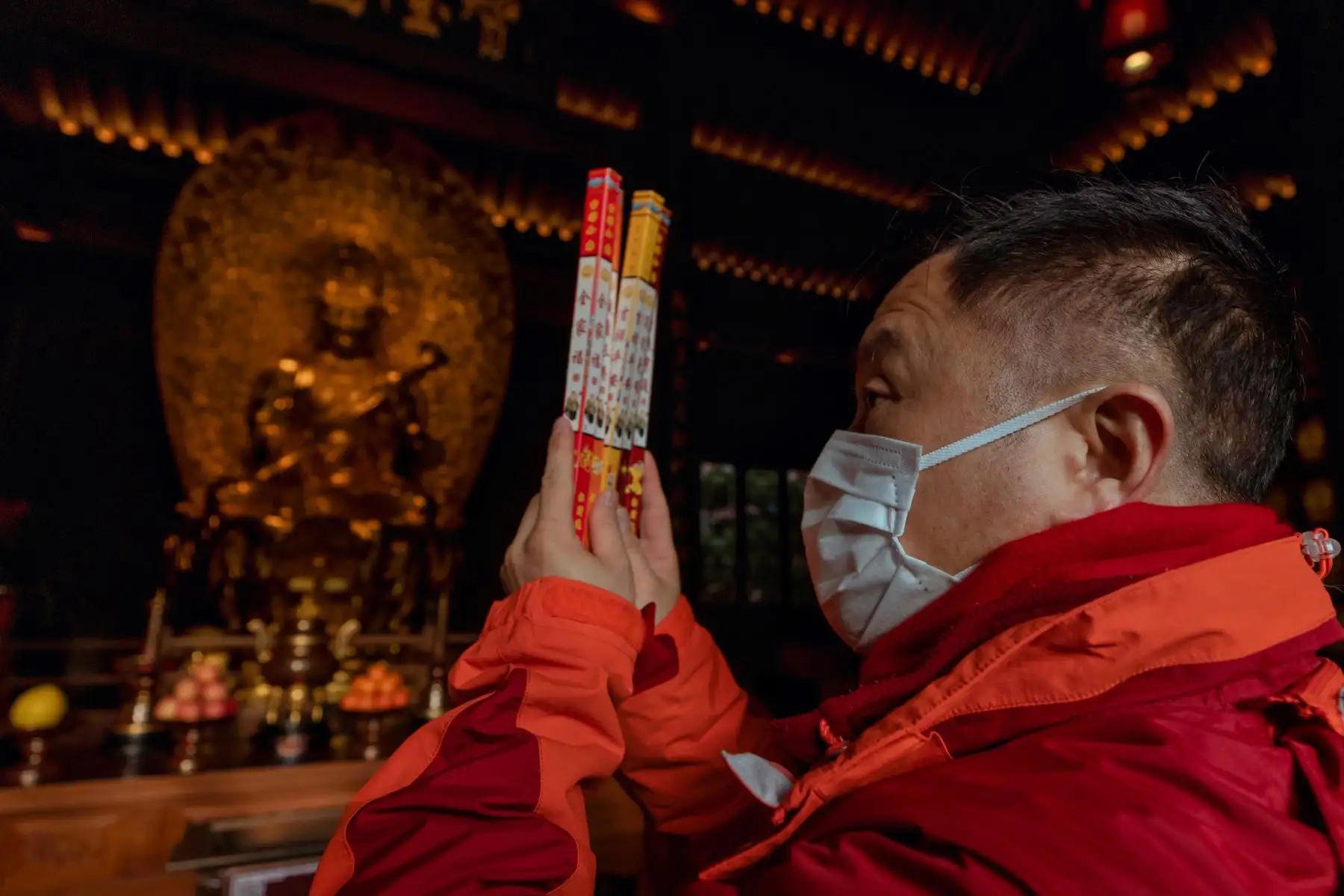 Un hombre quema varitas de incienso como ofrenda a sus antepasados ​​fallecidos y reza en el Templo del Buda de Jade en Shanghai, China. Foto: EFE