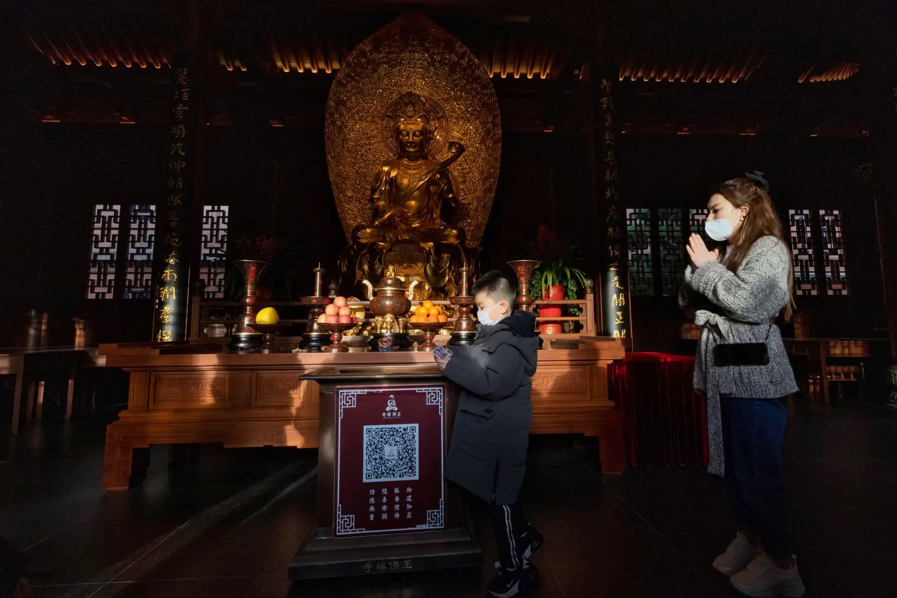 Un niño deja dinero como ofrenda mientras su madre reza en el Templo del Buda de Jade en Shanghai, durante el inicio del Nuevo Año Lunar, en China. Foto: EFE