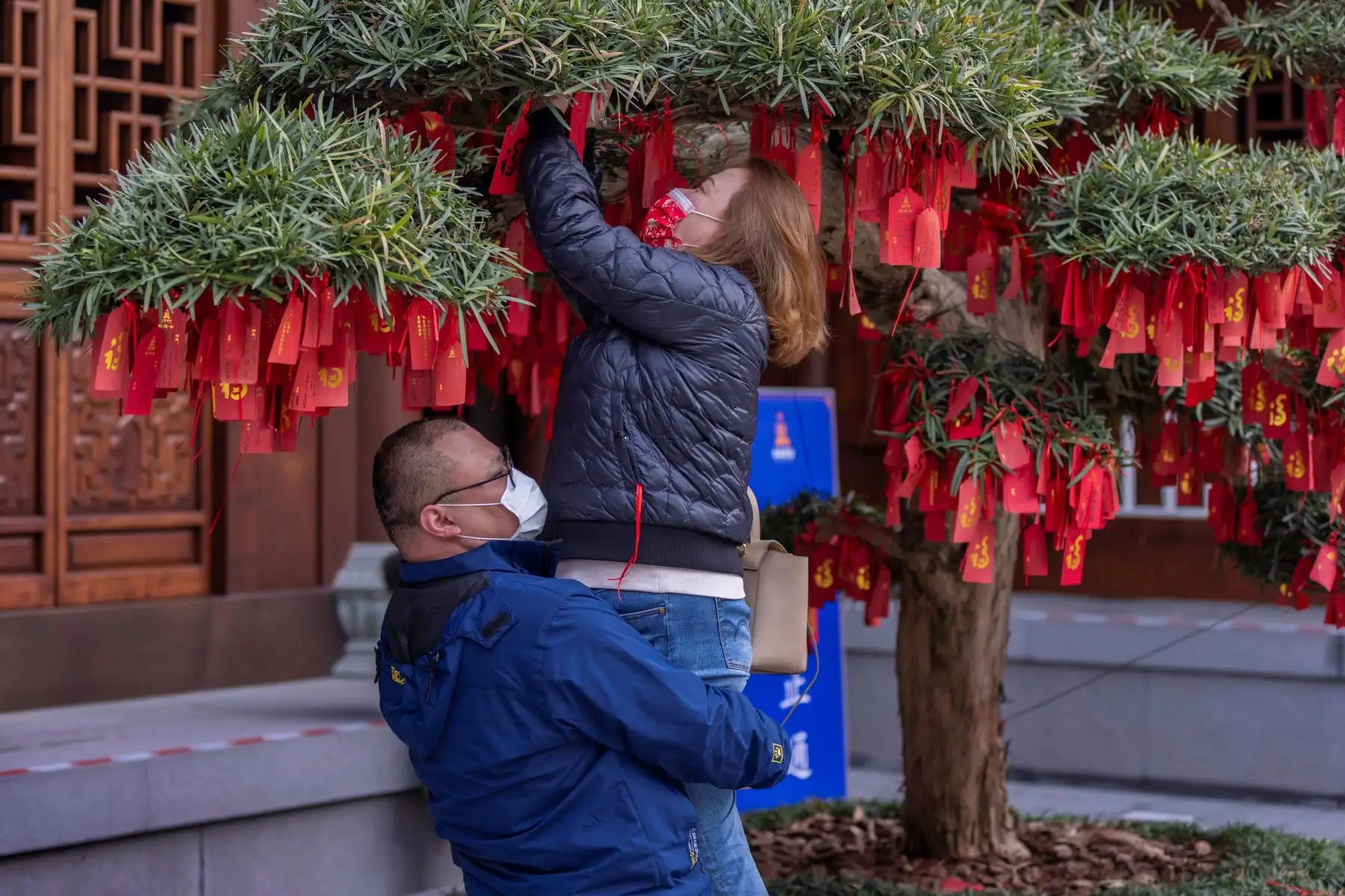 Un hombre ayuda a una mujer a colgar una oración escrita en el árbol de los deseos en el Templo del Buda de Jade en Shanghai, China. Foto: EFE