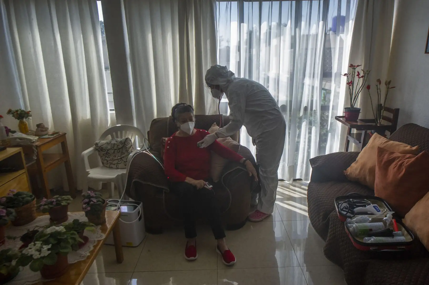 Karla Hitzuri Montano, cirujana médica, vestida con traje protector, escucha el corazón de su paciente Rosario Socorro, de 70 años, que padece la enfermedad del coronavirus COVID-19 en un barrio de la Ciudad de México, el 4 de febrero de 2021. Foto: AFP