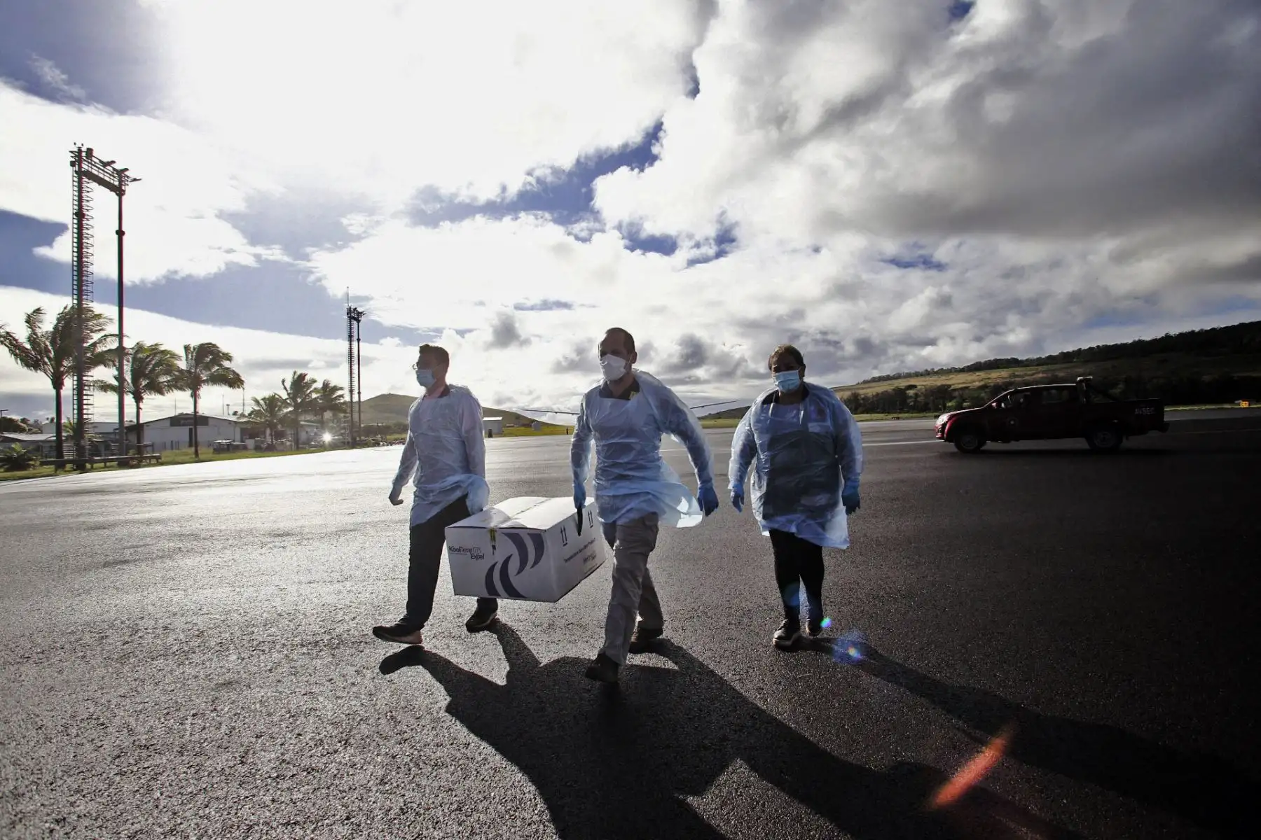 Trabajadores de la salud descargando una caja con casi 1200 dosis de la vacuna CoronaVac desarrollada por Sinovac, a su llegada al Aeropuerto Internacional de Isla de Pascua, en Rapa Nui, Chile, el 4 de febrero de 2021. Foto: AFP