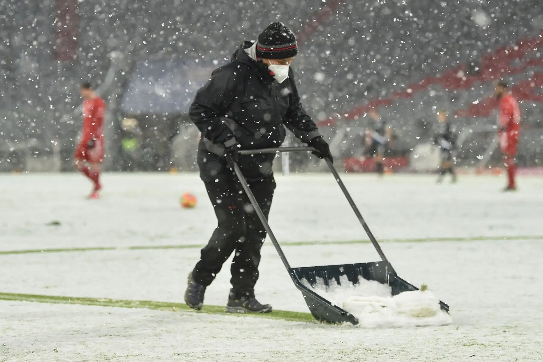 Un jardinero despeja las líneas del campo cubiertas nieve durante el partido de fútbol de la Bundesliga de la primera división alemana FC Bayern Munich vs. DSC Armenia Bielefeld en Munich, Alemania. Foto: AFP