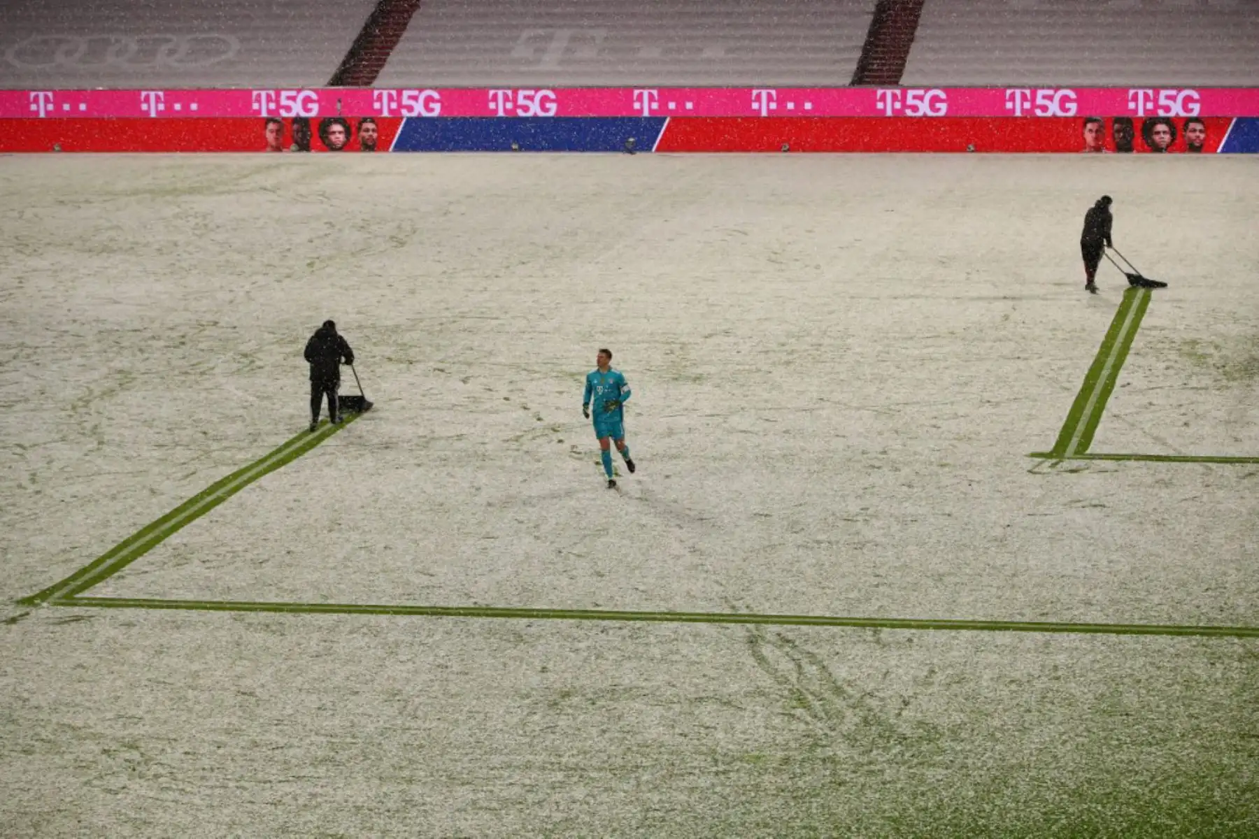 Los jardineros despejan las líneas alrededor de la caja de nieve mientras el portero alemán del Bayern Munich Manuel Neuer corre durante el partido de fútbol de la Bundesliga de primera división alemana FC Bayern Munich contra DSC Armenia Bielefeld en Munich.

Foto:AFP