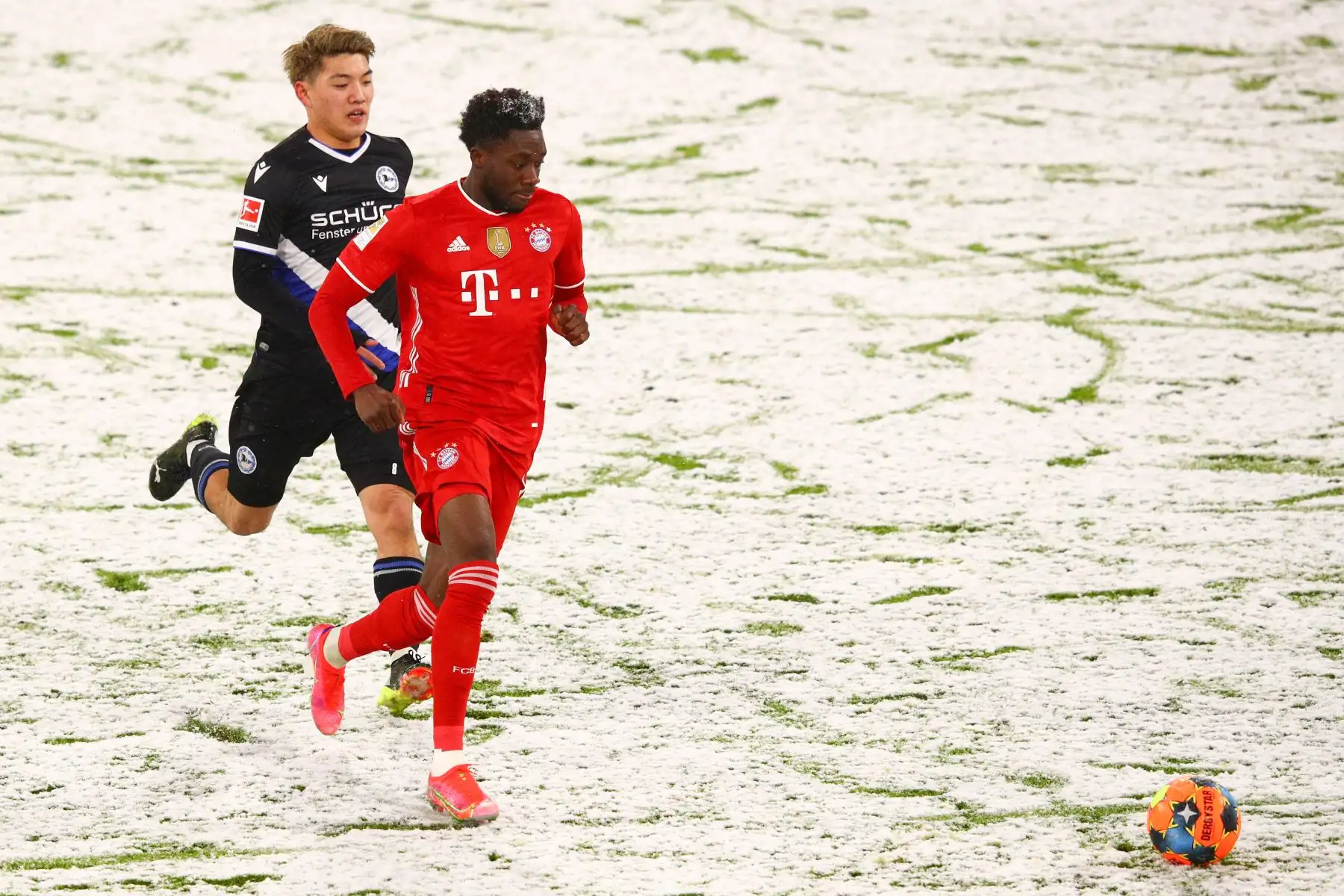 El delantero japonés de Bielefeld, Ritsu Doan y el mediocampista canadiense del Bayern Munich, Alphonso Davies, compiten por el balón durante el partido de fútbol de la Bundesliga. Foto: AFP
