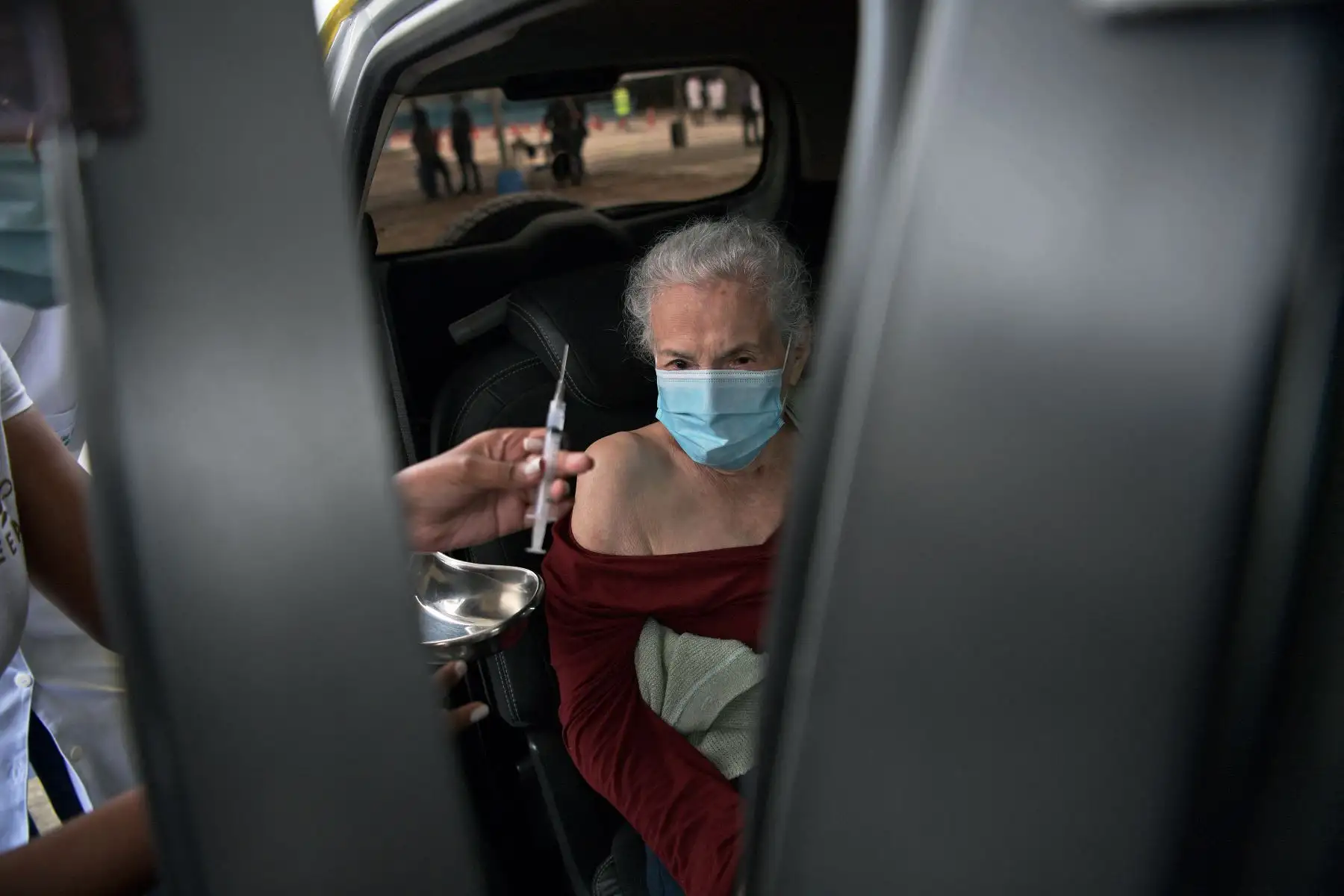 Una anciana brasileña recibe una dosis de la vacuna Coronavac en un paseo por el centro de vacunación en el recinto del Carnaval Sambódromo de Río, en Río de Janeiro. Foto: AFP