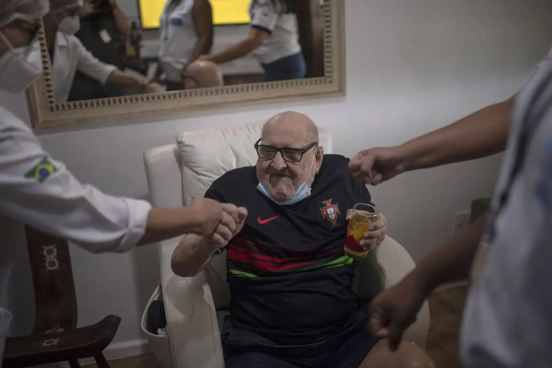 Jose Nunes Passagem, 95, celebra el saludo a los Profesionales de la Salud de la Clínica Pública Sergio Vieira de Mello luego de recibir una dosis de la vacuna CoronaVac de Sinovac Biotech contra COVID-19 dentro de su casa. Foto: AFP