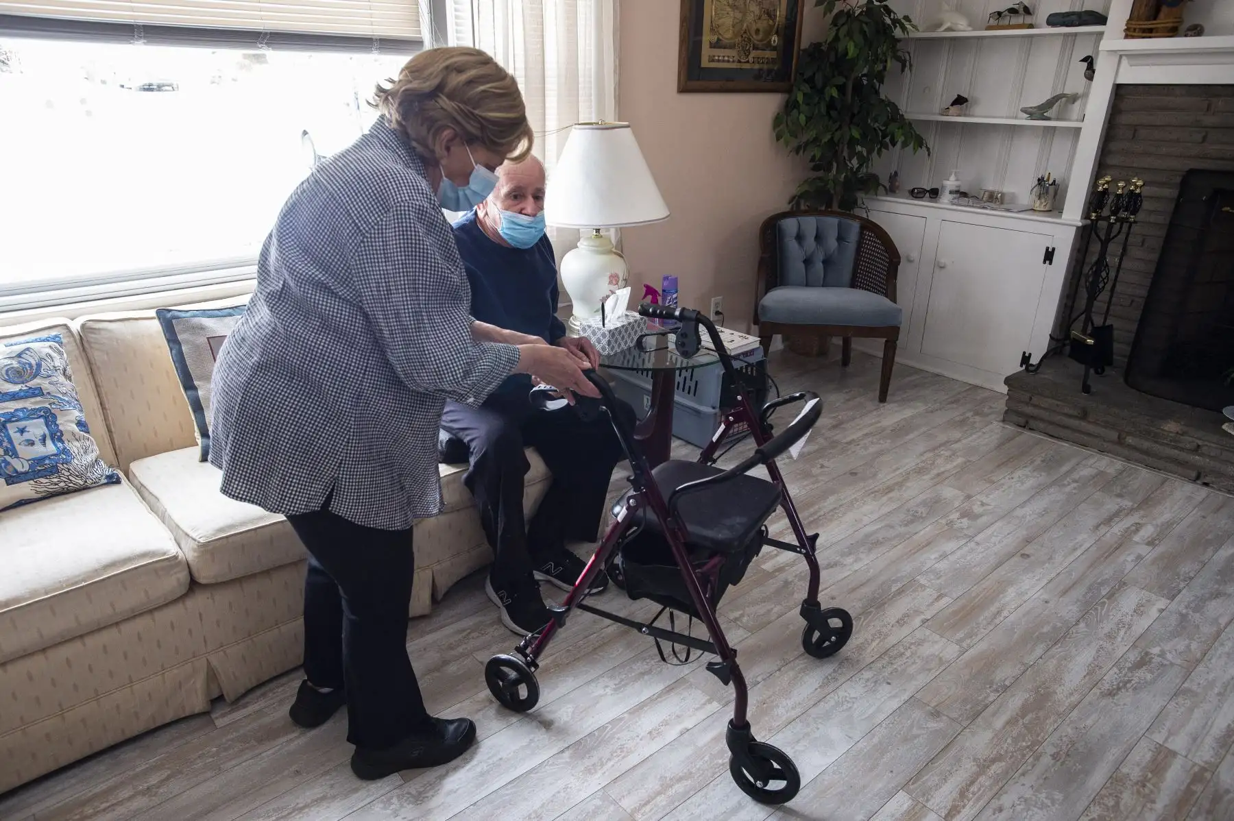 Rose Mowel ayuda a su esposo Stanley a sentarse en un sofá antes de mudarse para que la enfermera visitante le aplique la vacuna Moderna Covid-19 en su casa en Connecticut, Estados Unidos. Foto: AFP