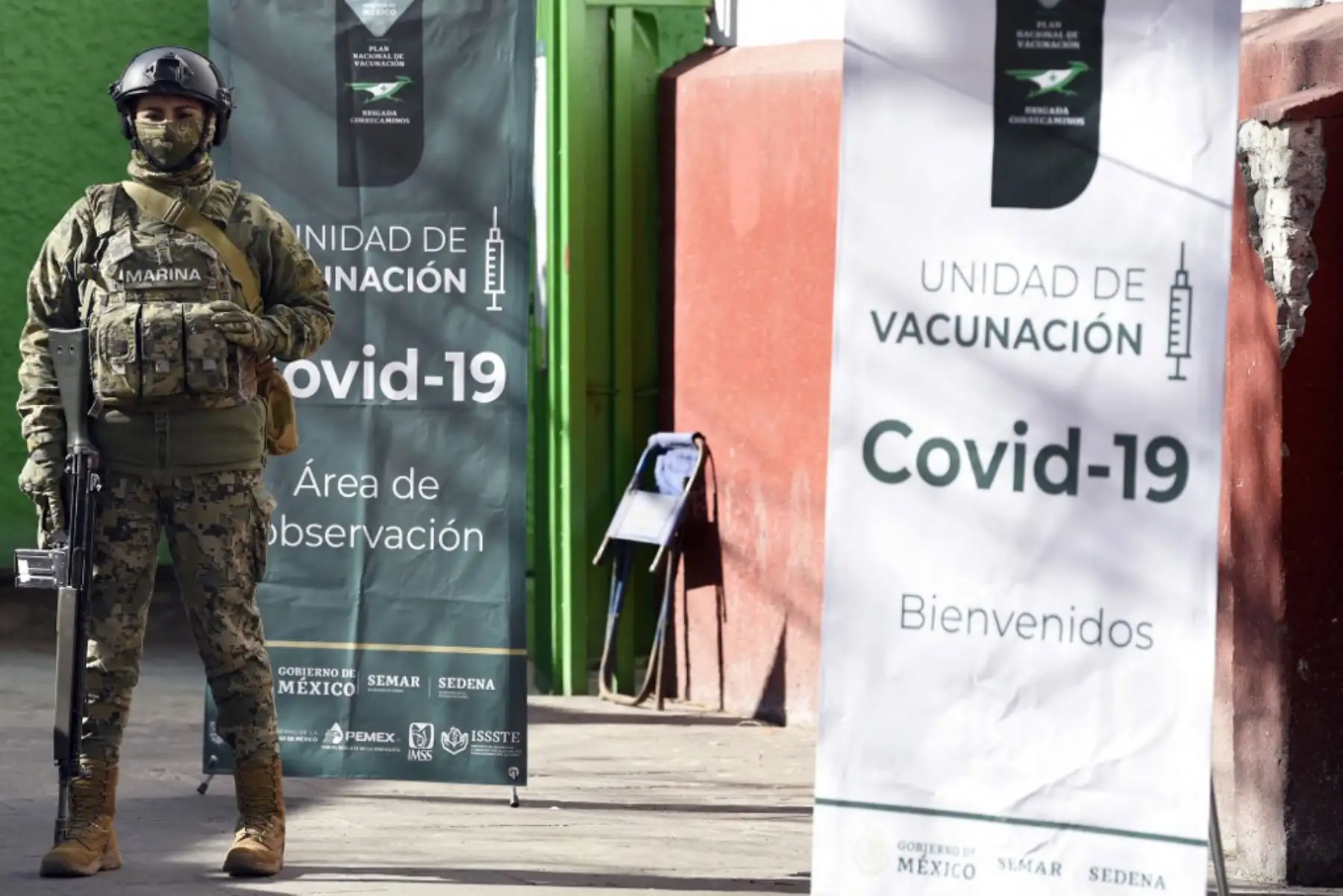Un miembro de la Armada de México custodia la entrada de un centro de vacunación mientras personas mayores de 60 años comienzan a recibir la primera dosis de la vacuna AstraZeneca contra COVID-19, en el barrio San Pedro Atocpan del municipio de Milpa Alta en la Ciudad de México.

Foto: AFP