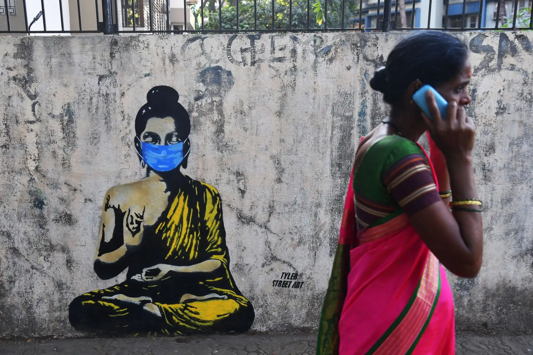 Un residente pasa junto a un graffiti de Lord Gautam Buddha con una mascarilla en medio de preocupaciones sobre la propagación del nuevo coronavirus COVID-19, en Mumbai, el 16 de marzo de 2020. Foto: AFP