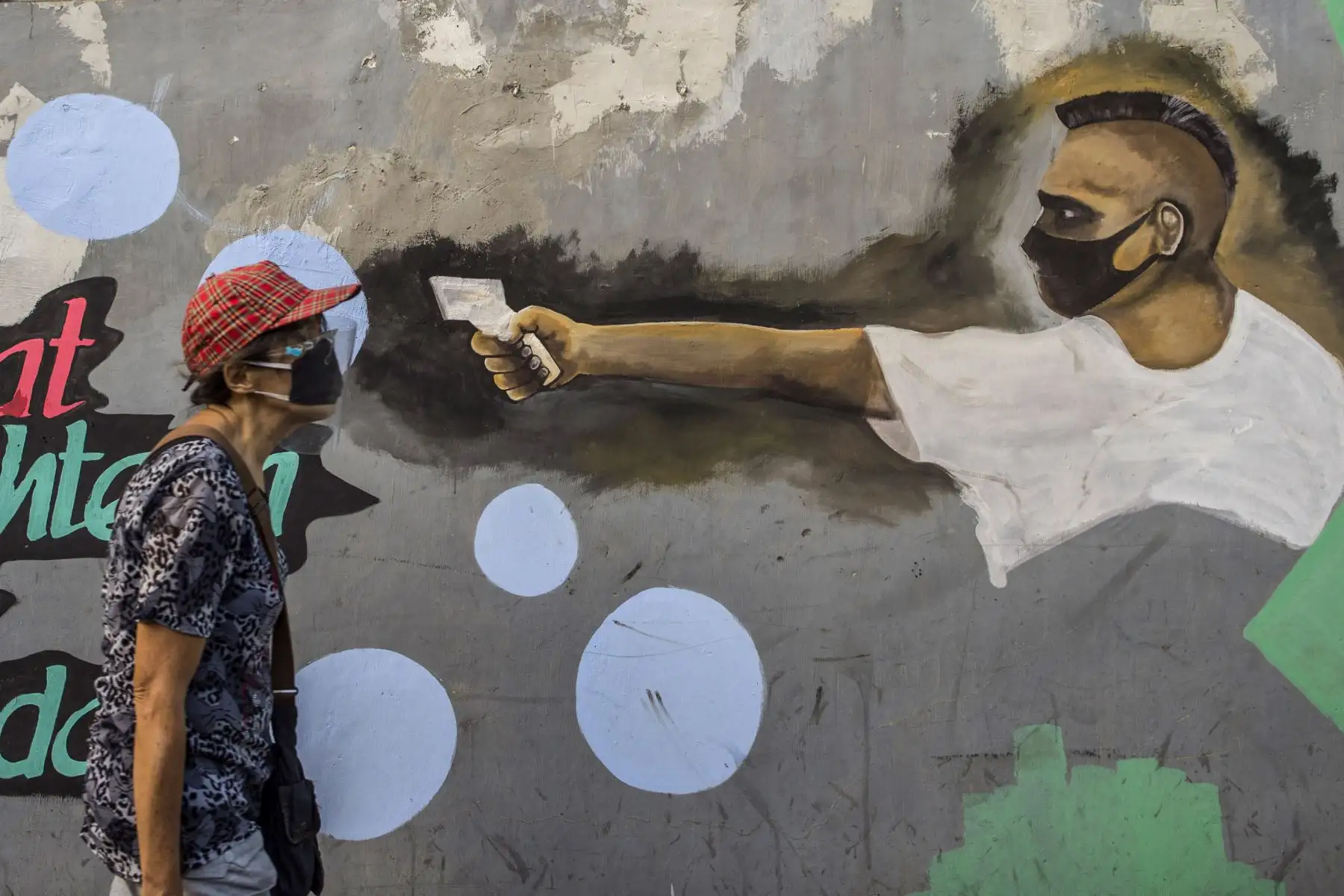 Una anciana pasa junto a un mural que representa el coronavirus COVID-19 en Surabaya, Java Oriental. Foto: AFP