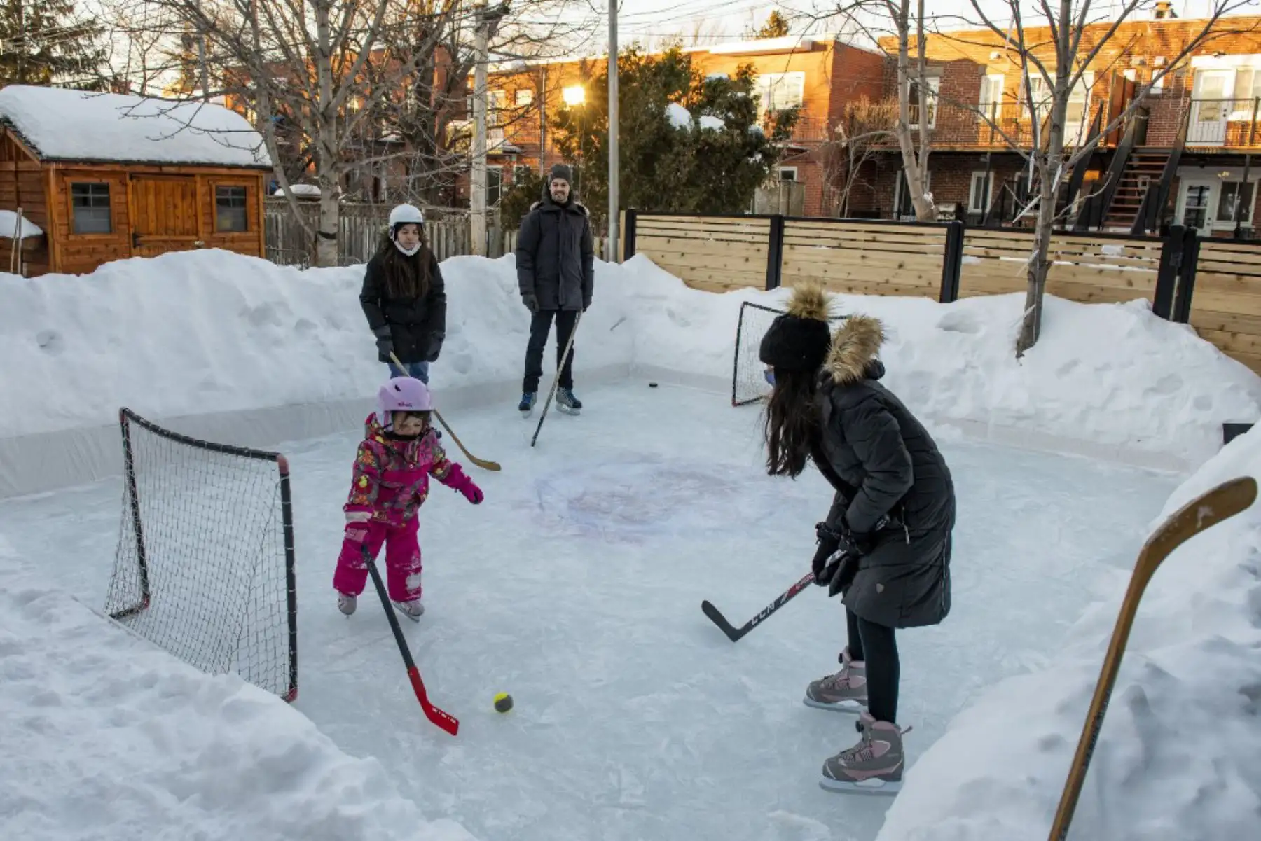 Felix Rheaume (C) y su familia juegan al hockey en la pista de hielo de su patio trasero en Montreal, Quebec. Más canadienses que nunca, ya que las autoridades de salud pública han restringido las reuniones públicas y otras actividades sociales, este año están abrazando a una antigua tradición invernal en este país: la pista de patinaje sobre hielo que les permite patinar y jugar al hockey sobre hielo, el pasatiempo nacional de Canadá, y al mismo tiempo evitar contactos, más allá de sus familiares y amigos