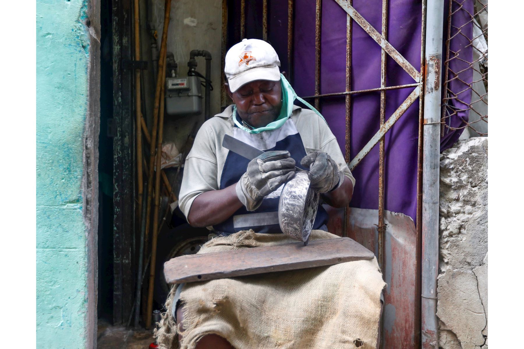 Un limpiador de calderos trabaja hoy en la puerta de su casa, en La Habana (Cuba). A pesar del avance de la pandemia en Cuba, donde se registraron 923 casos este jueves, la mitad de ellos en La Habana, los habitantes de la capital cubana continúan con su laborioso día a día. EFE/Yander Zamora