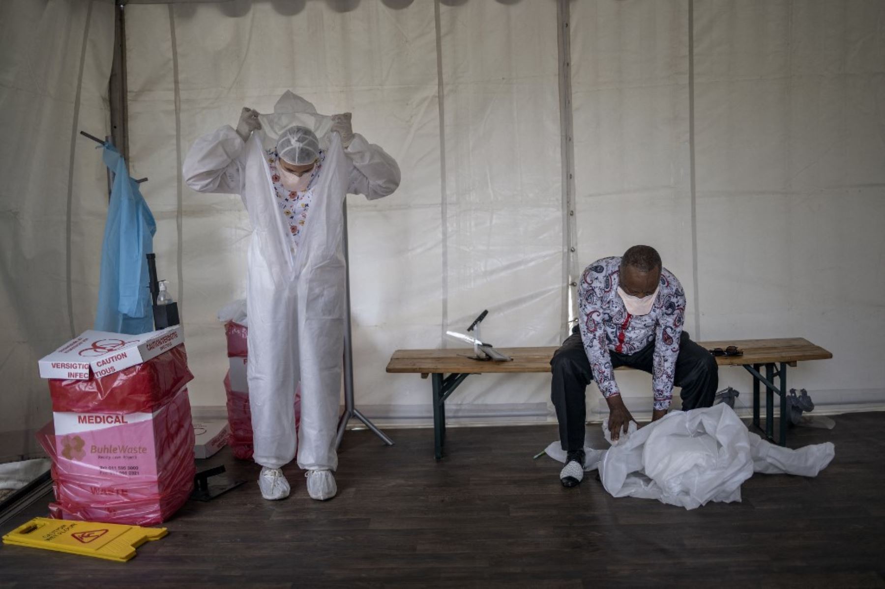 Trabajadores de la salud desechan su equipo de protección personal fuera de una de las salas temporales dedicadas al tratamiento de posibles pacientes con coronavirus covid-19 en el Hospital de Campo Nasrec en Soweto. Foto: AFP