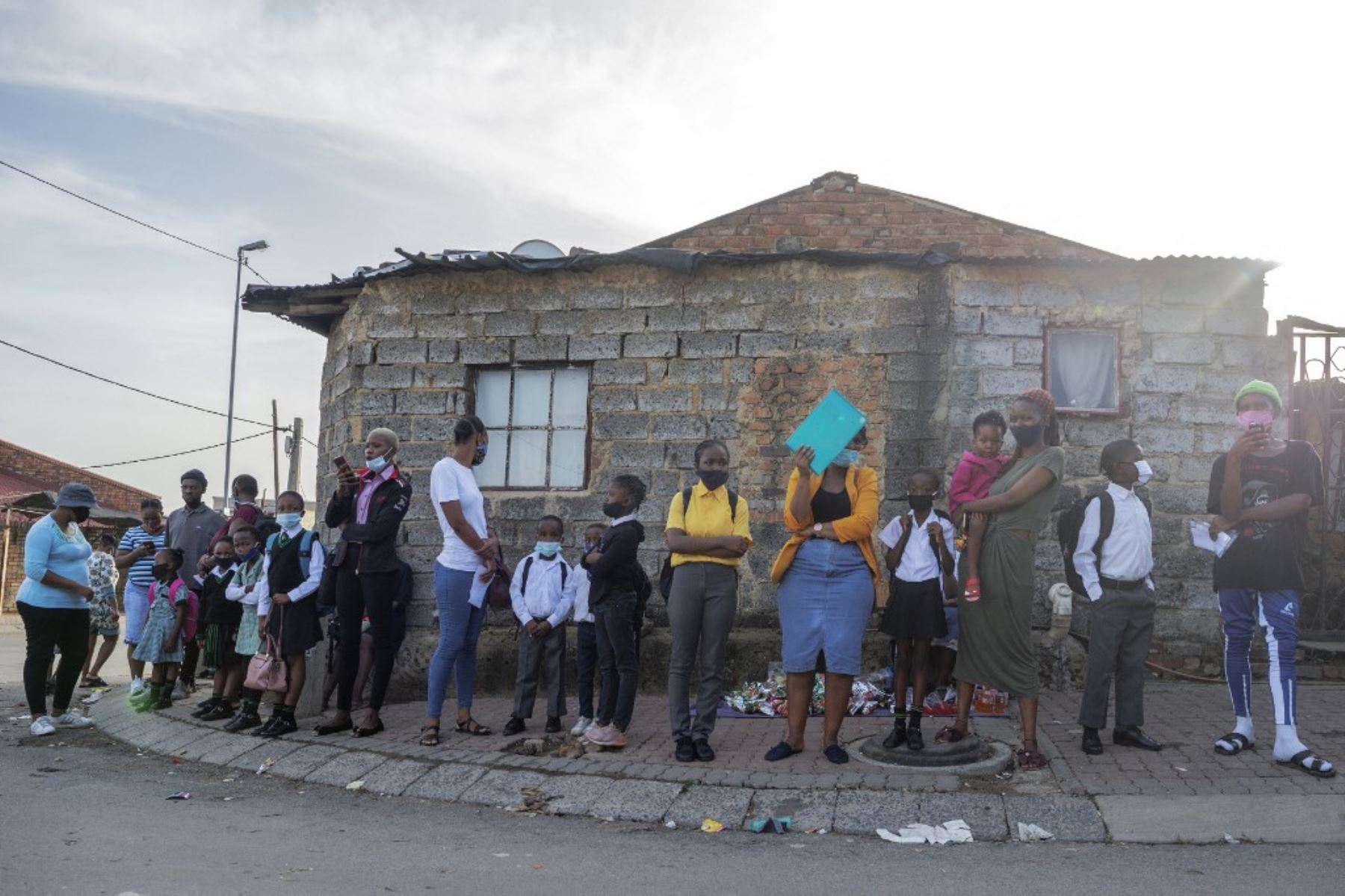 Los alumnos y sus familiares hacen cola frente a la entrada de la Escuela Primaria Superior Ithute, durante el primer día del nuevo año académico, en Alexandra, Johannesburgo. Foto: AFP