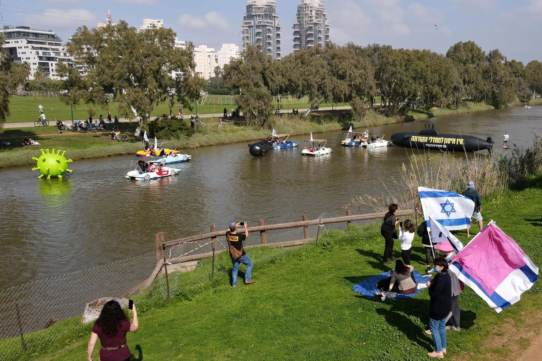 Objetos inflables que incluyen un virus y submarinos, navegan por el río Yarkon, mientras los israelíes protestan en medio de la crisis de la pandemia del coronavirus contra su primer ministro, exigiendo su renuncia, en la ciudad costera de Tel Aviv.
Foto: AFP
