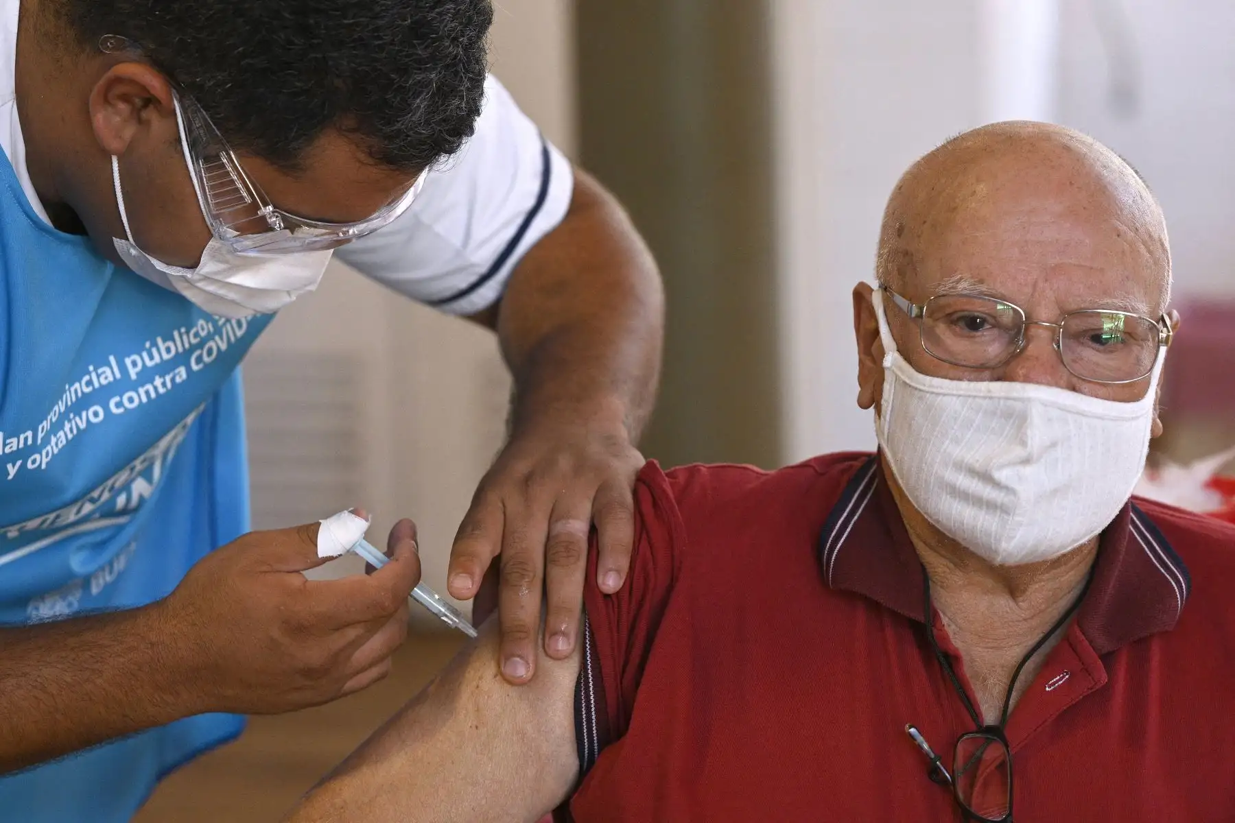 Un trabajador de salud aplica una dosis de la vacuna Sputnik V contra COVID-19, a un anciano en un centro de vacunación temporal en una escuela pública en Ezeiza, afueras de Buenos Aires. Foto: AFP