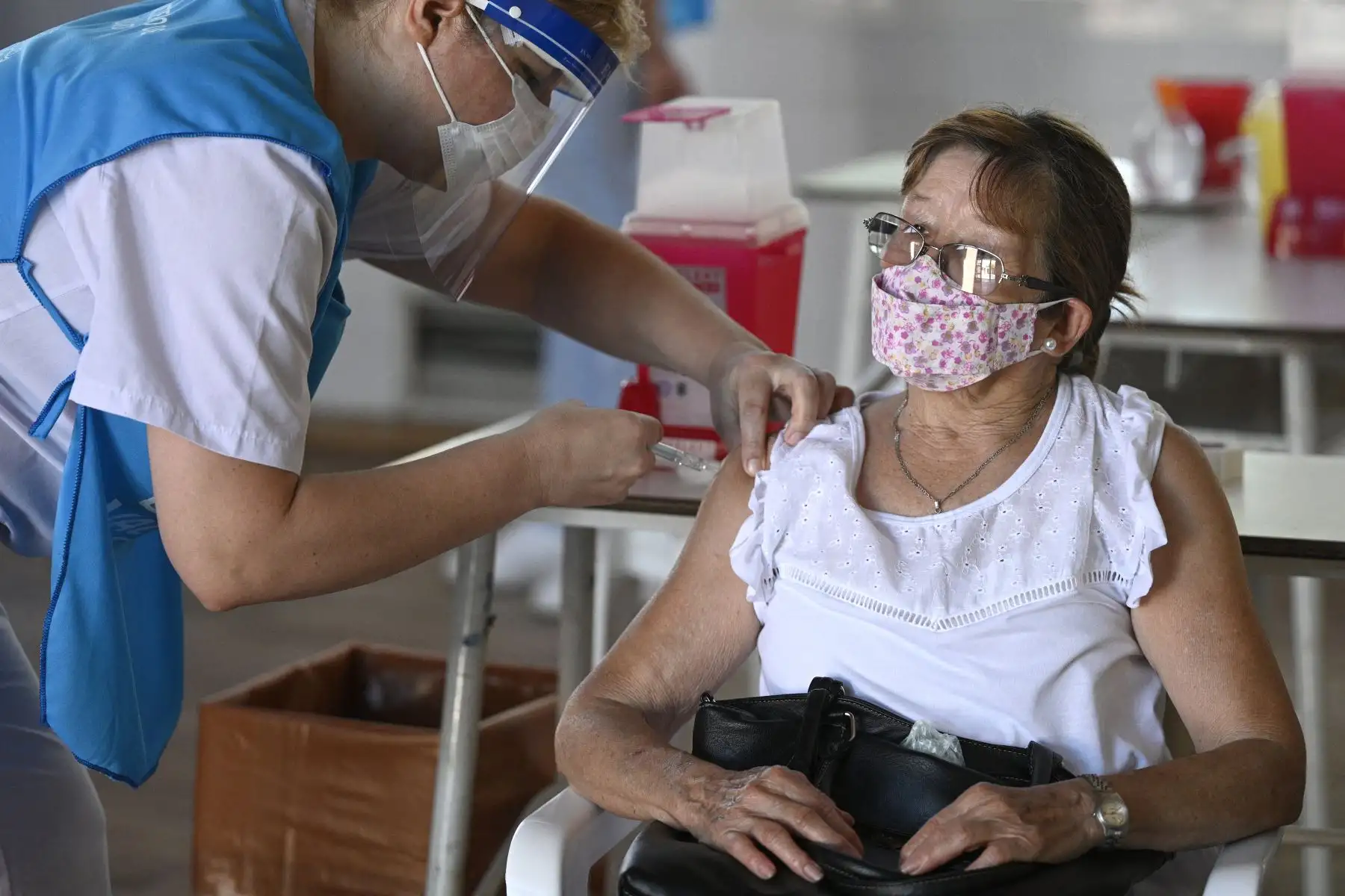 Un trabajador de salud aplica una dosis de la vacuna Sputnik V contra COVID-19, a una anciana en un centro de vacunación temporal en una escuela pública en Ezeiza, en las afueras de Buenos Aires. Foto: AFP