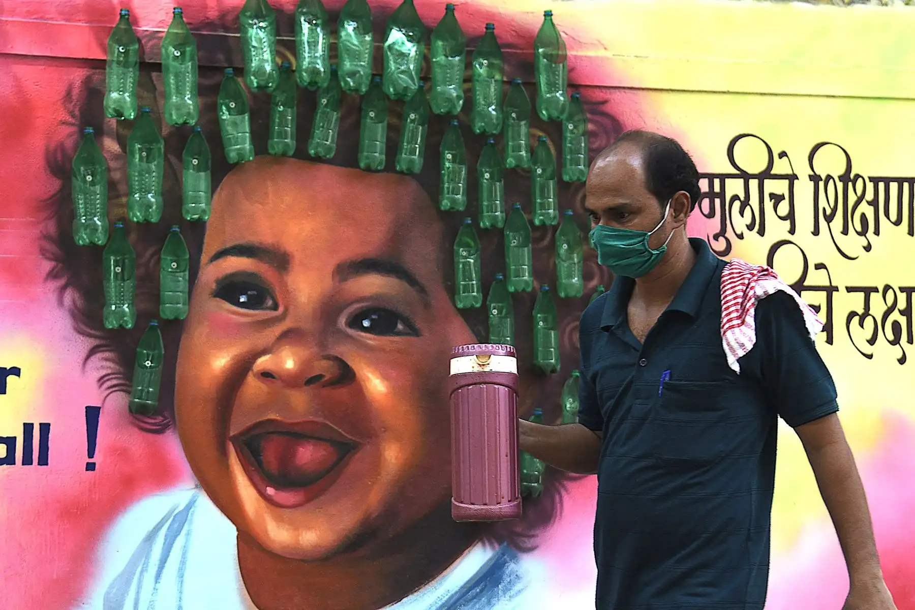 Un hombre con una mascarilla pasa junto a un mural después de que las autoridades impusieran nuevas restricciones como medida preventiva contra la propagación del coronavirus Covid-19, en Mumbai. Desde el comienzo de la epidemia más de 111.331.990 personas contrajeron la enfermedad. De ellas al menos 68.323.000 se recuperaron, según las autoridades. Foto: AFP