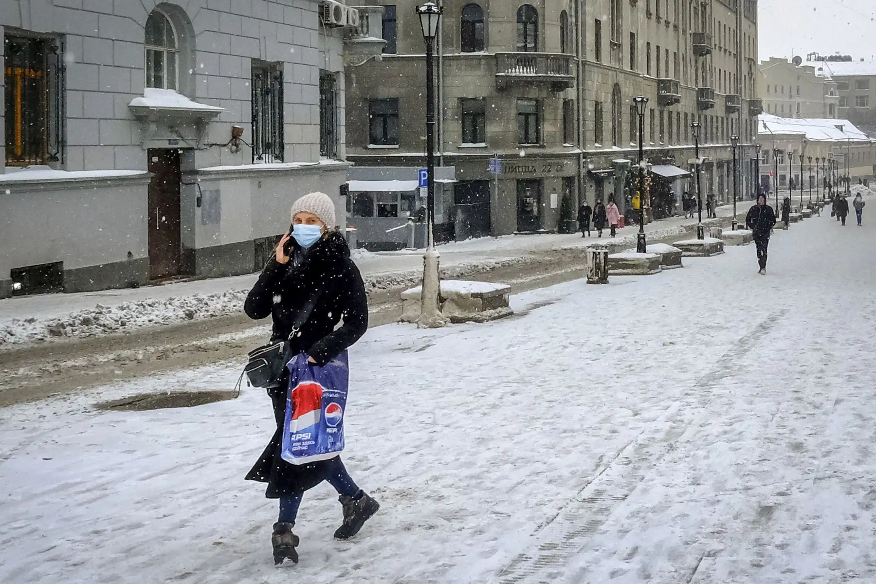 Una mujer con una mascarilla protectora contra la pandemia Covid-19, camina en la nieve por una calle en el centro de Moscú. Desde el comienzo de la epidemia más de 111.331.990 personas contrajeron la enfermedad. De ellas al menos 68.323.000 se recuperaron, según las autoridades. Foto: AFP