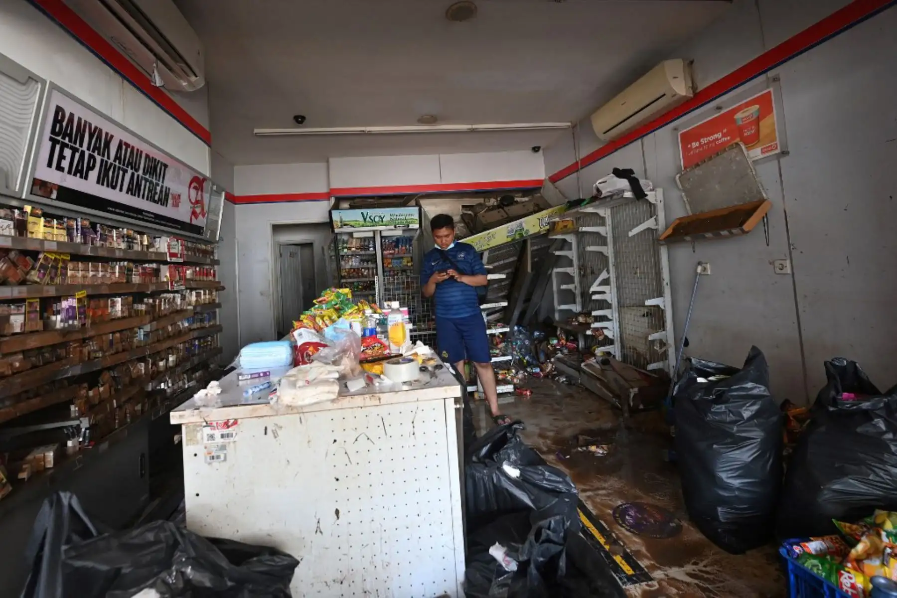 Un hombre observa los daños a una tienda en Kemang en Yakarta, después que partes de la capital de Indonesia se inundaron por las fuertes lluvias estacionales.

Foto: AFP