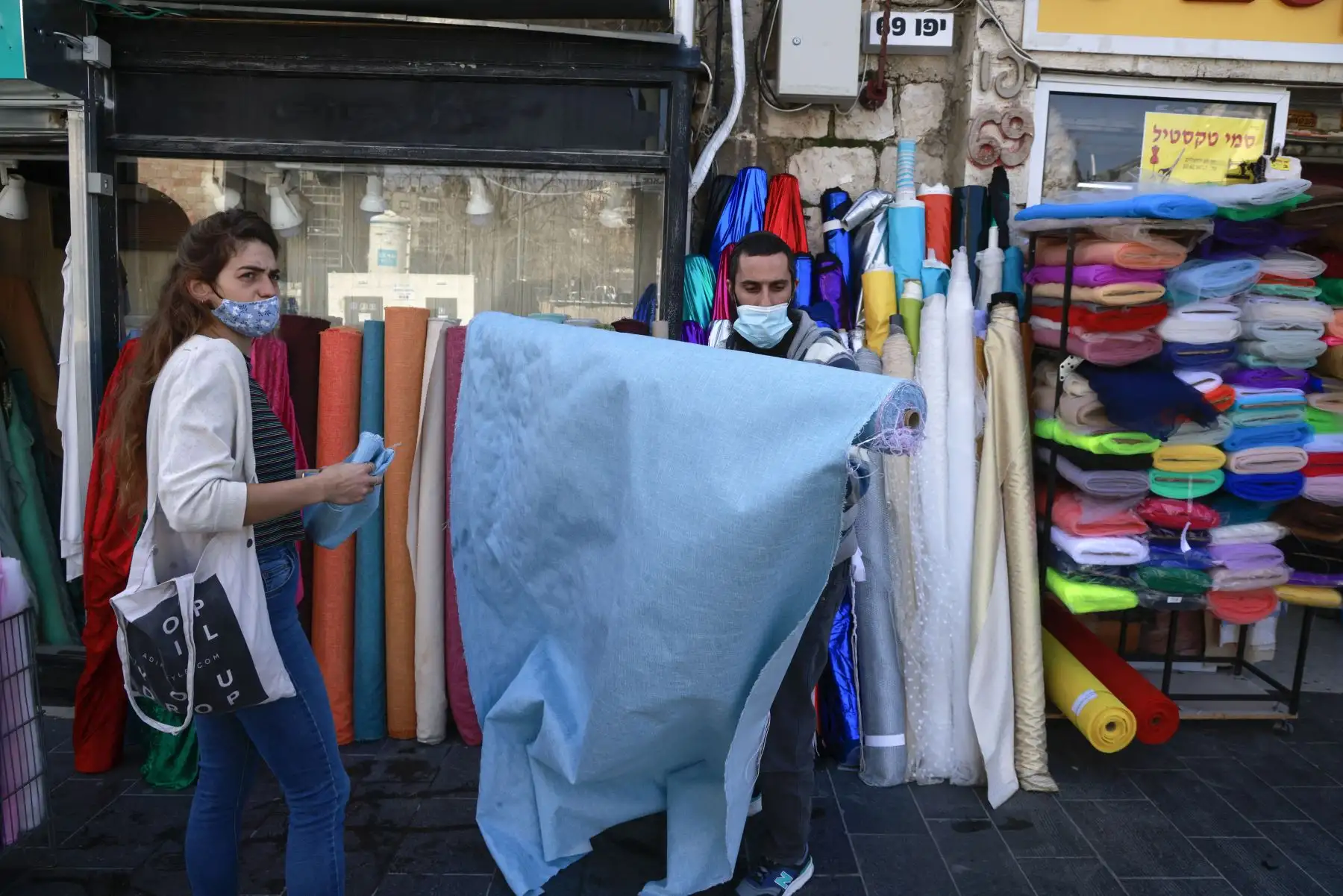 Una mujer compra telas en una tienda abierta en Jerusalén, el 7 de febrero de 2021, después de que las autoridades israelíes anunciaran un alivio gradual de las restricciones por el coronavirus. Foto: AFP