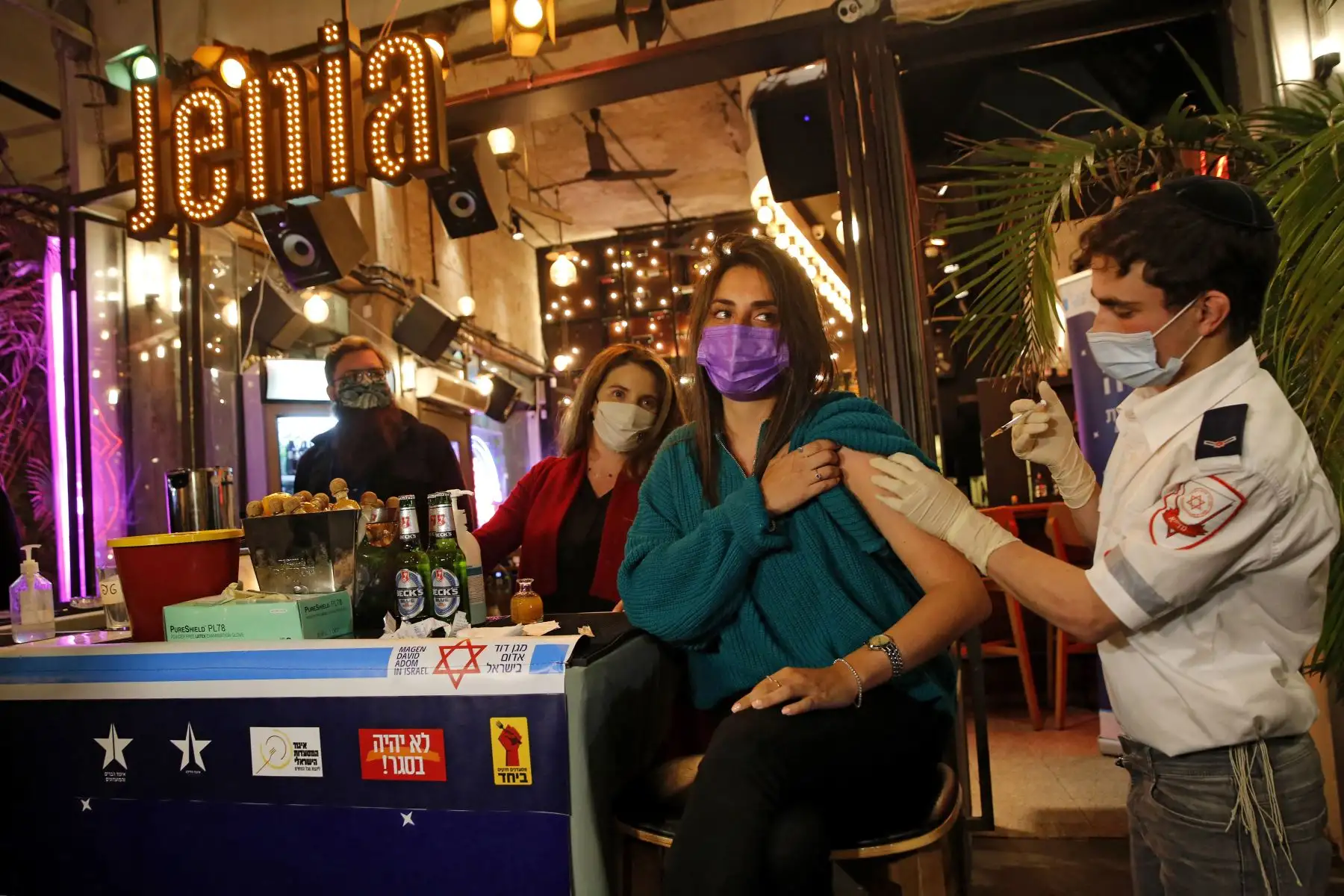 Un trabajador de salud administra la vacuna COVID-19 a un israelí en un bar en la ciudad costera de Tel Aviv, en Israel. Foto: AFP