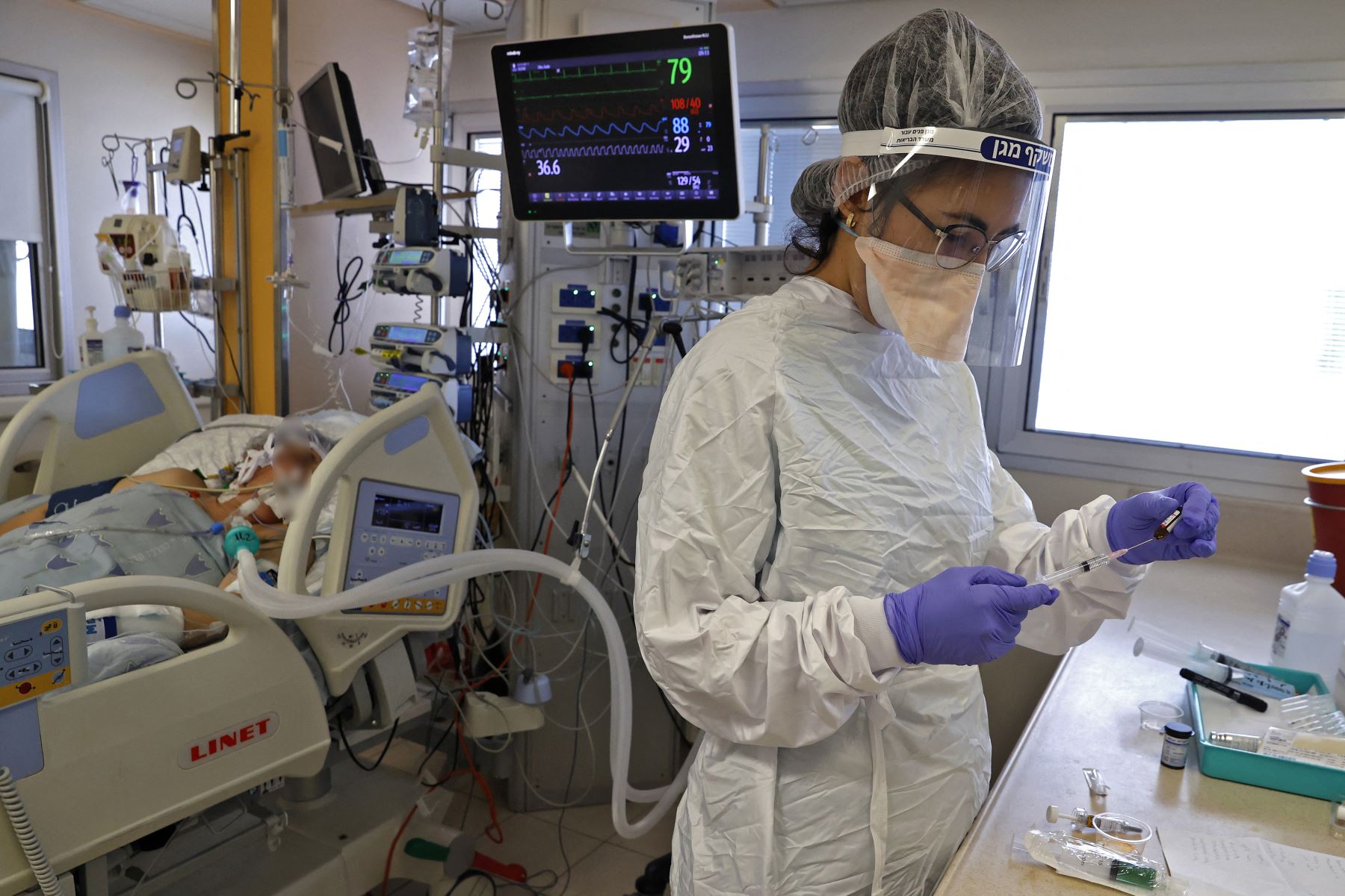Un trabajador de la salud atiende a un paciente de Covid-19 en una sala de aislamiento en el Centro Médico Ichilov en Tel Aviv, en Israel. Foto: AFP