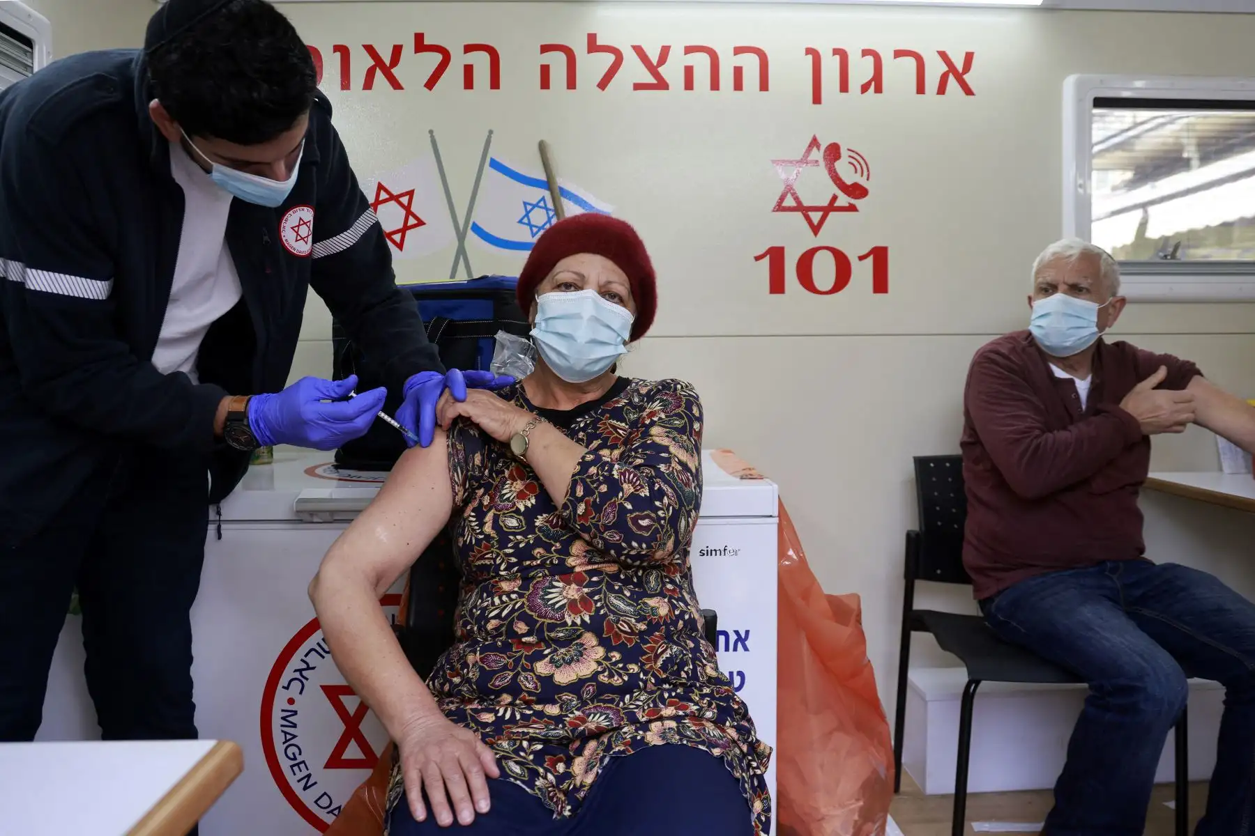 Un paramédico administra una dosis de la vacuna contra el coronavirus de Pfizer BioNTech a una mujer dentro de una clínica móvil de Magen David Adom en el mercado Mahane Yehuda en Jerusalén, el 22 de febrero de 2021. Foto: AFP