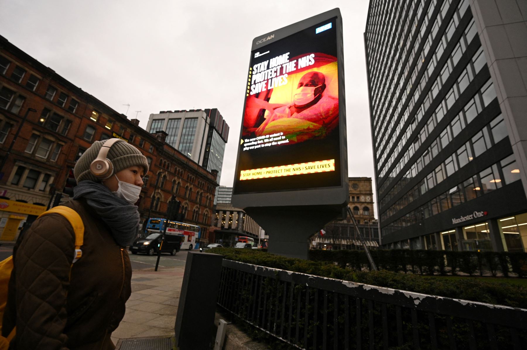 Un peatón que cubre la cara pasa junto a un cartel informativo del Gobierno Covid-19 en Manchester, norte de Inglaterra, el 19 de febrero de 2021, mientras la vida continúa bajo el tercer bloqueo británico por coronavirus. Foto: AFP