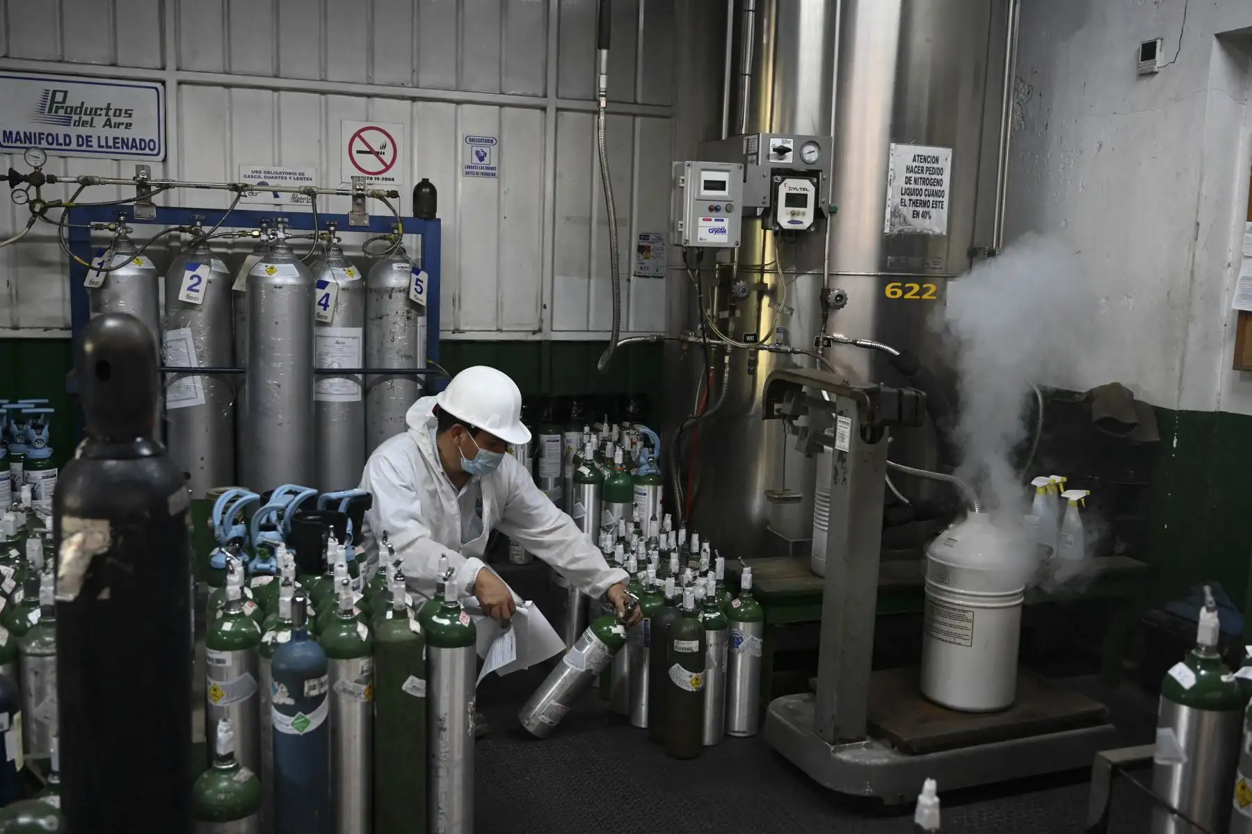 Un empleado revisa los tanques de oxígeno luego de ser rellenados para ser distribuidos a hospitales y personas infectadas con el coronavirus COVID-19, en la Ciudad de Guatemala, el 5 de febrero de 2021. Foto: AFP