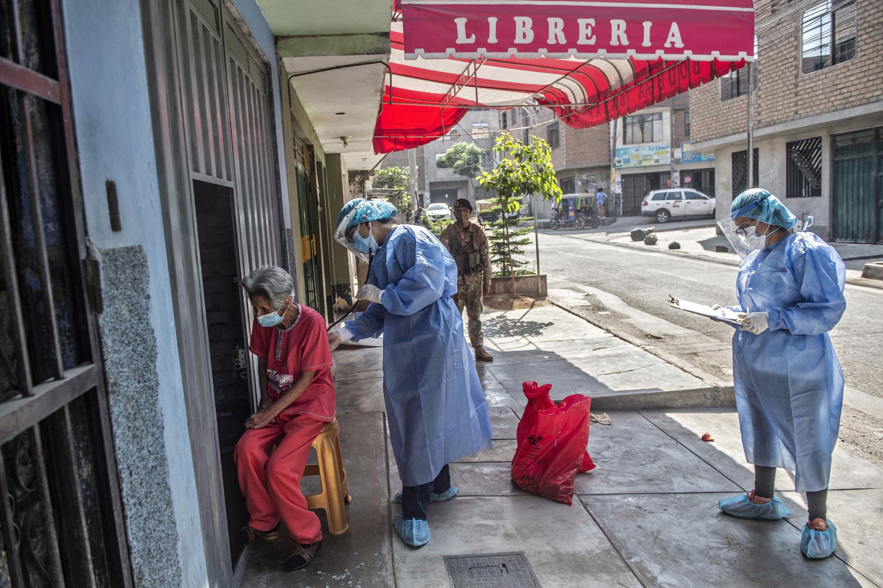 Un trabajador del Ministerio de Salud examina a una anciana en el distrito de Ate, en Lima, el 23 febrero del 2021. Foto: AFP
