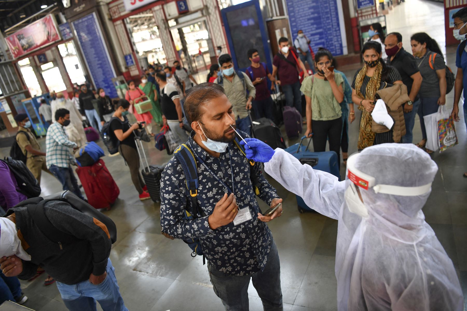 Un trabajador de la salud con equipo de protección toma una muestra de hisopado nasal de los pasajeros que llegan para realizar pruebas de coronavirus en el terminal ferroviario de Mumbai, el 22 de febrero de 2021. Foto: AFP