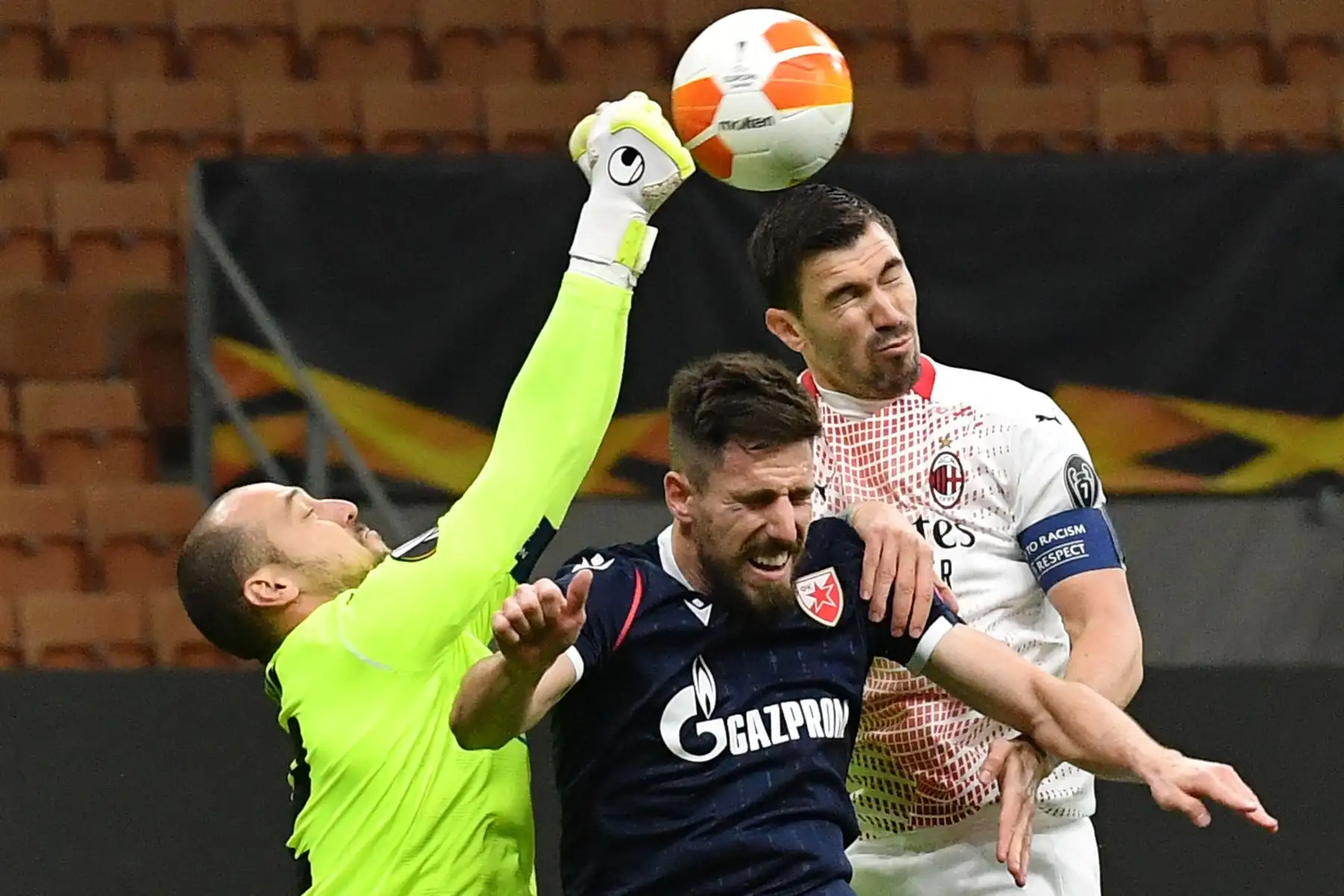 El portero canadiense del Crvena Zvezda Beograd, Milan Borjan, desvía un disparo mientras el defensor australiano del Crvena Zvezda Beograd, Milos Degenek y el defensor italiano del AC Milan Alessio Romagnoli, van de cabeza durante los dieciseisavos de final de la UEFA Europa League. Foto: AFP
