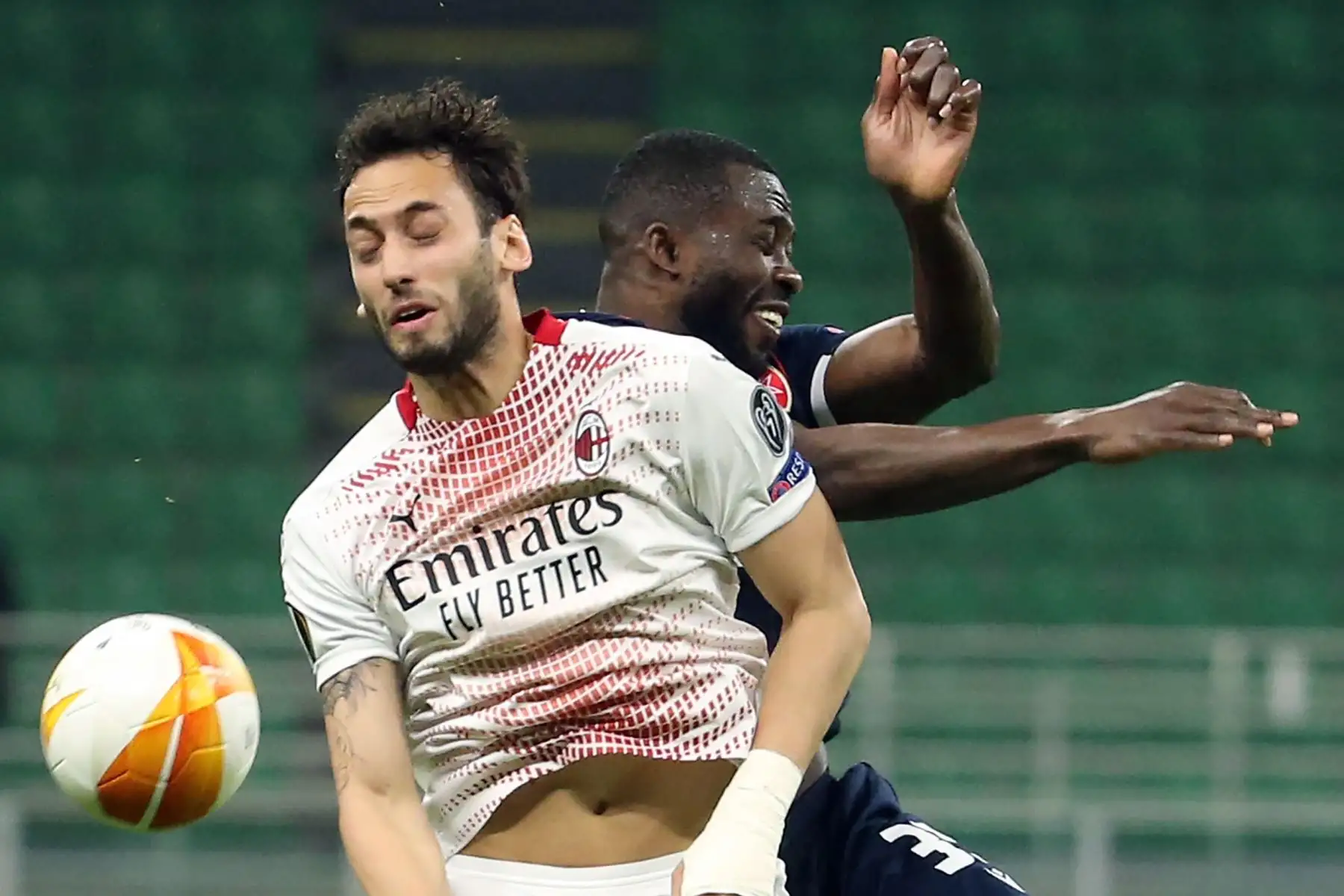 Hakan Calhanoglu del AC Milan desafía el balón con Sekou Sanogo del Estrella Roja de Belgrado durante los dieciseisavos de final de la UEFA Europa League. Foto: EFE
