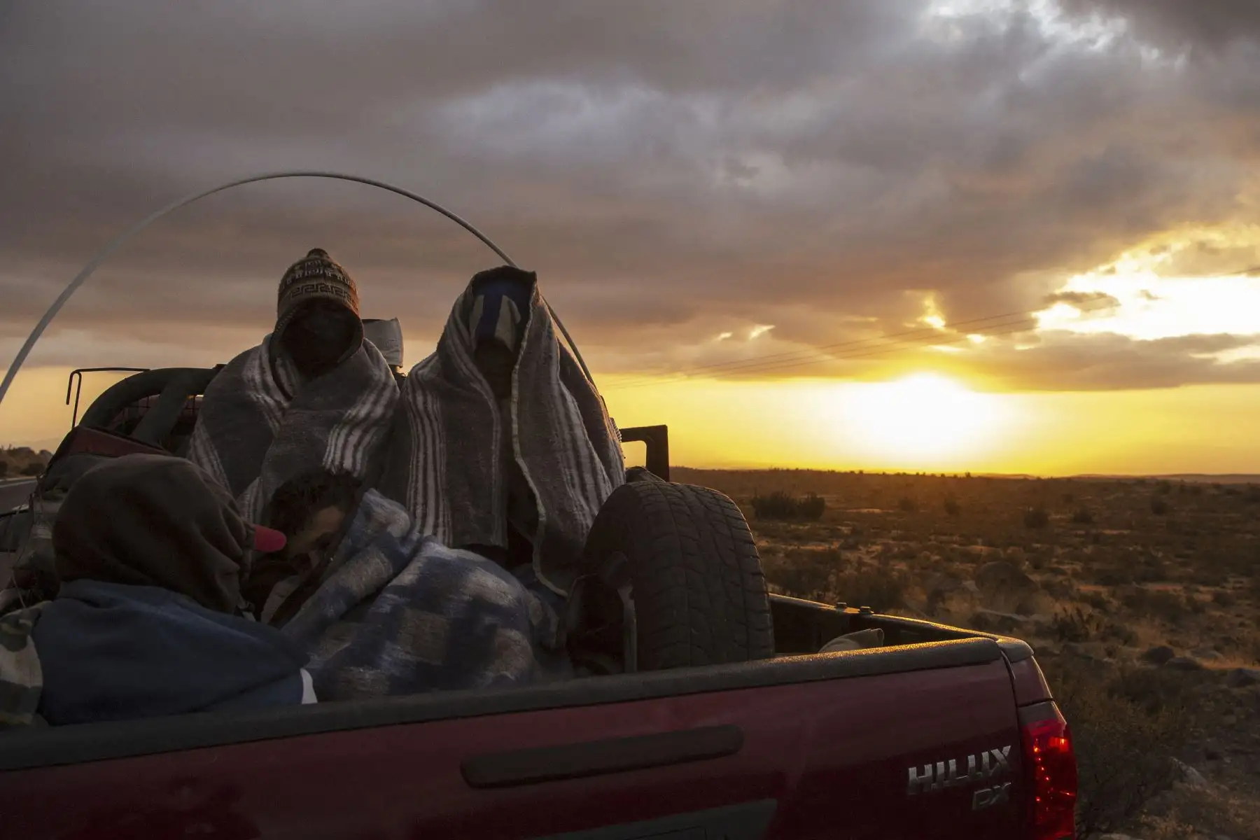 El migrante venezolano Rubi Alexander G. y amigos viajan en la parte trasera de un camión por la Ruta 15, luego de cruzar Bolivia hacia Chile. Foto: AFP